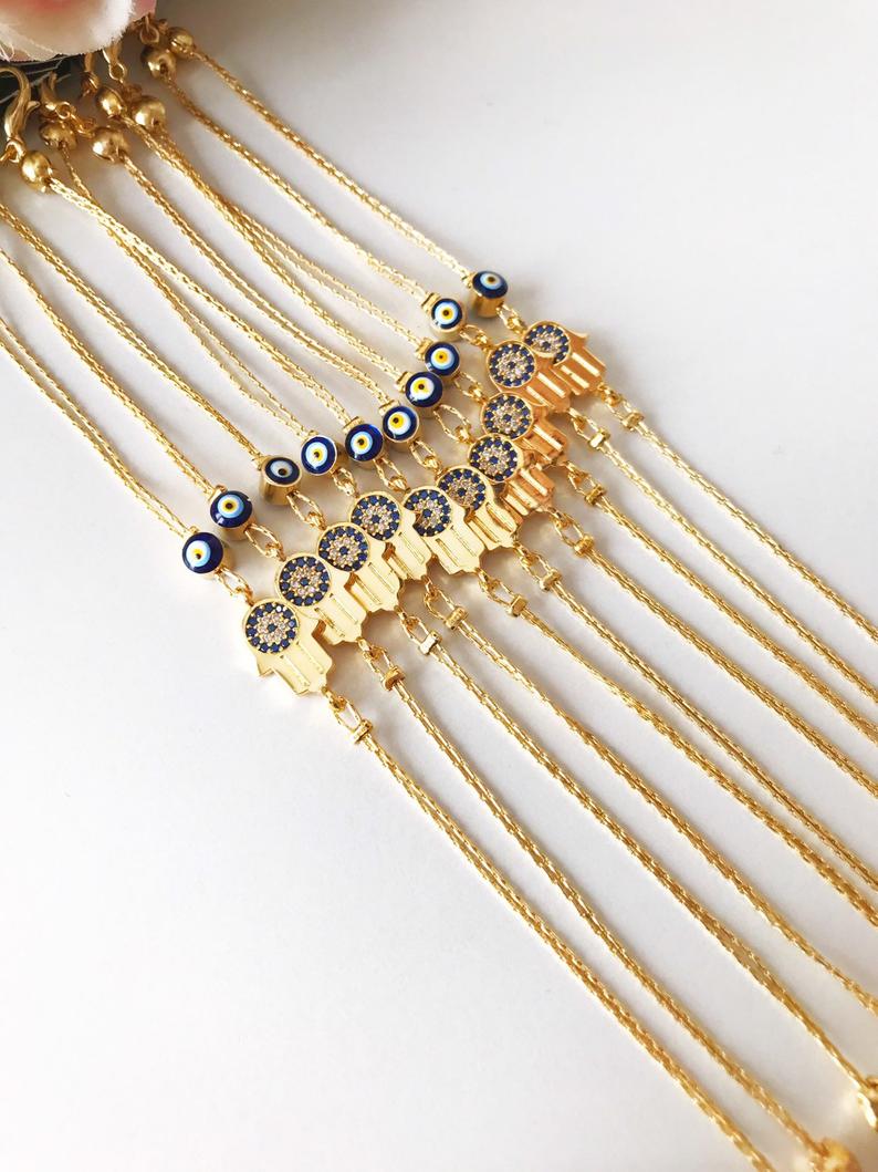 A beautiful handmade Hamsa Evil Eye Bracelet featuring a gold chain, hamsa charm, and evil eye beads, symbolizing protection and good fortune.