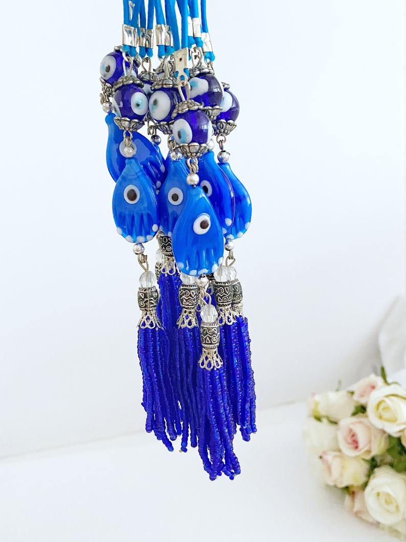 A beautifully crafted Hamsa hand evil eye car mirror charm featuring blue glass beads and a stylish tassel, perfect for car decor.