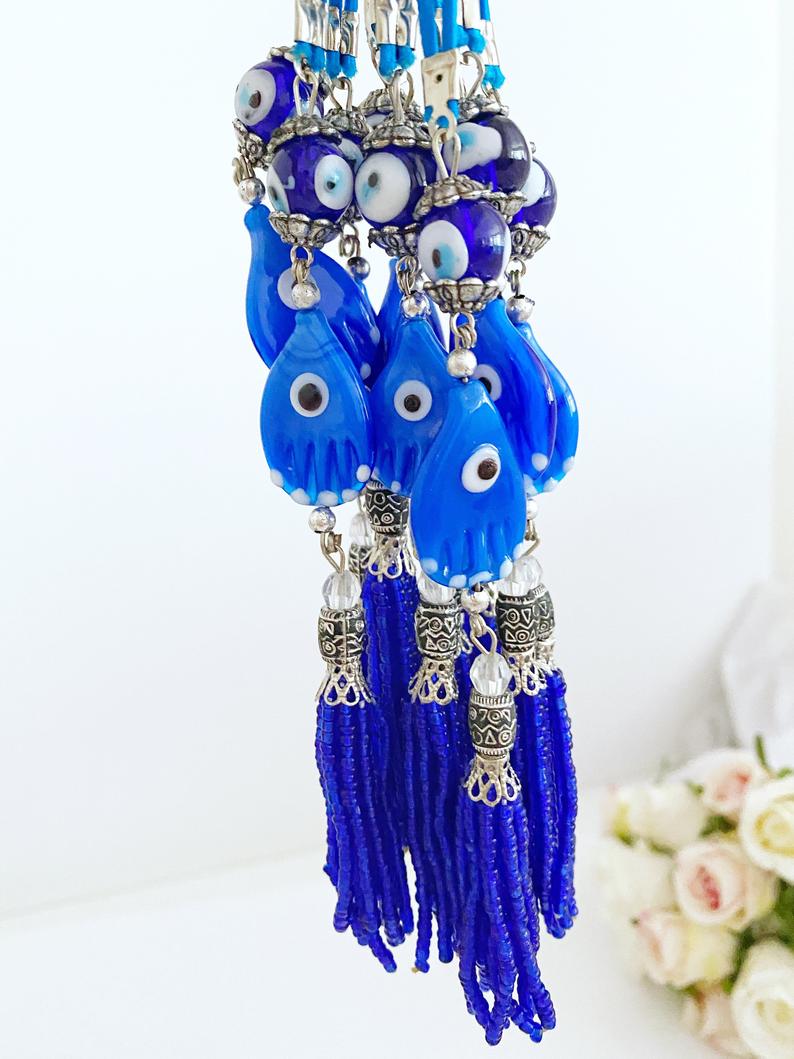 A beautifully crafted Hamsa hand evil eye car mirror charm featuring blue glass beads and a stylish tassel, perfect for car decor.