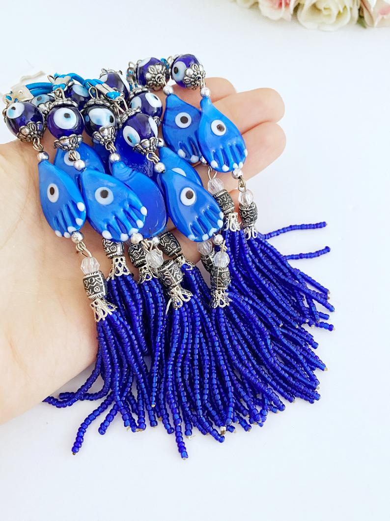 A beautifully crafted Hamsa hand evil eye car mirror charm featuring blue glass beads and a stylish tassel, perfect for car decor.
