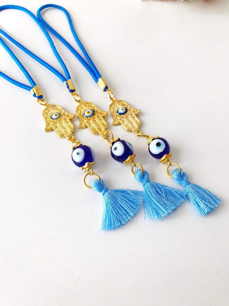 A beautifully crafted Hamsa hand evil eye car mirror charm featuring vibrant blue glass beads, symbolizing protection and good luck.