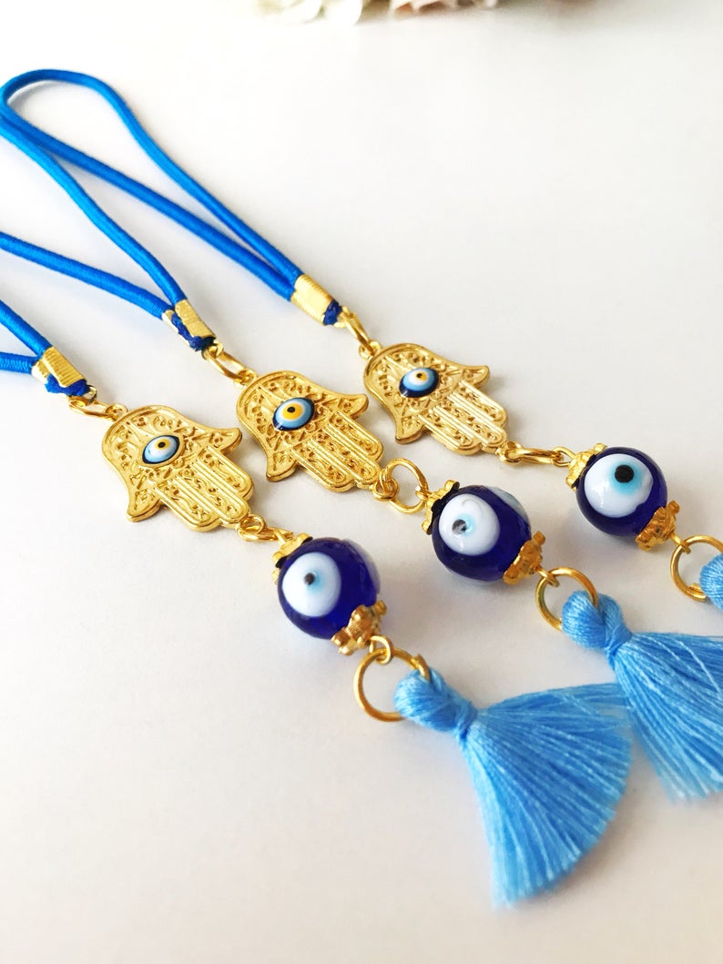 A beautifully crafted Hamsa hand evil eye car mirror charm featuring vibrant blue glass beads, symbolizing protection and good luck.