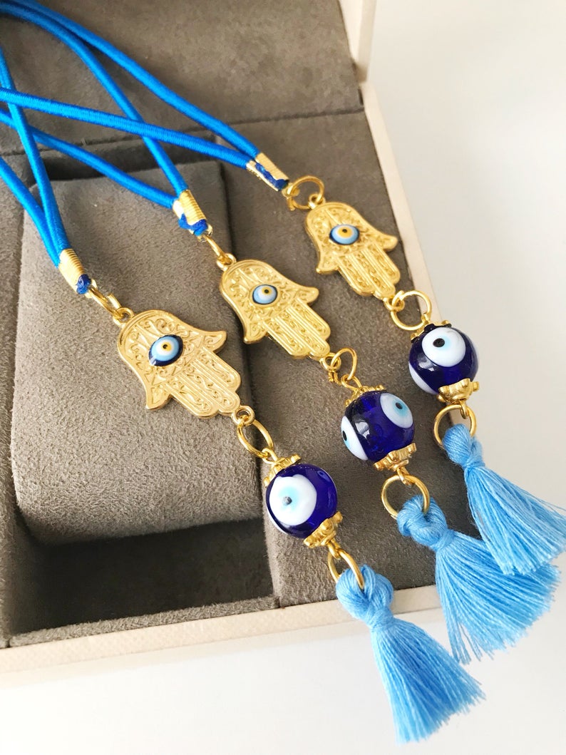 A beautifully crafted Hamsa hand evil eye car mirror charm featuring vibrant blue glass beads, symbolizing protection and good luck.