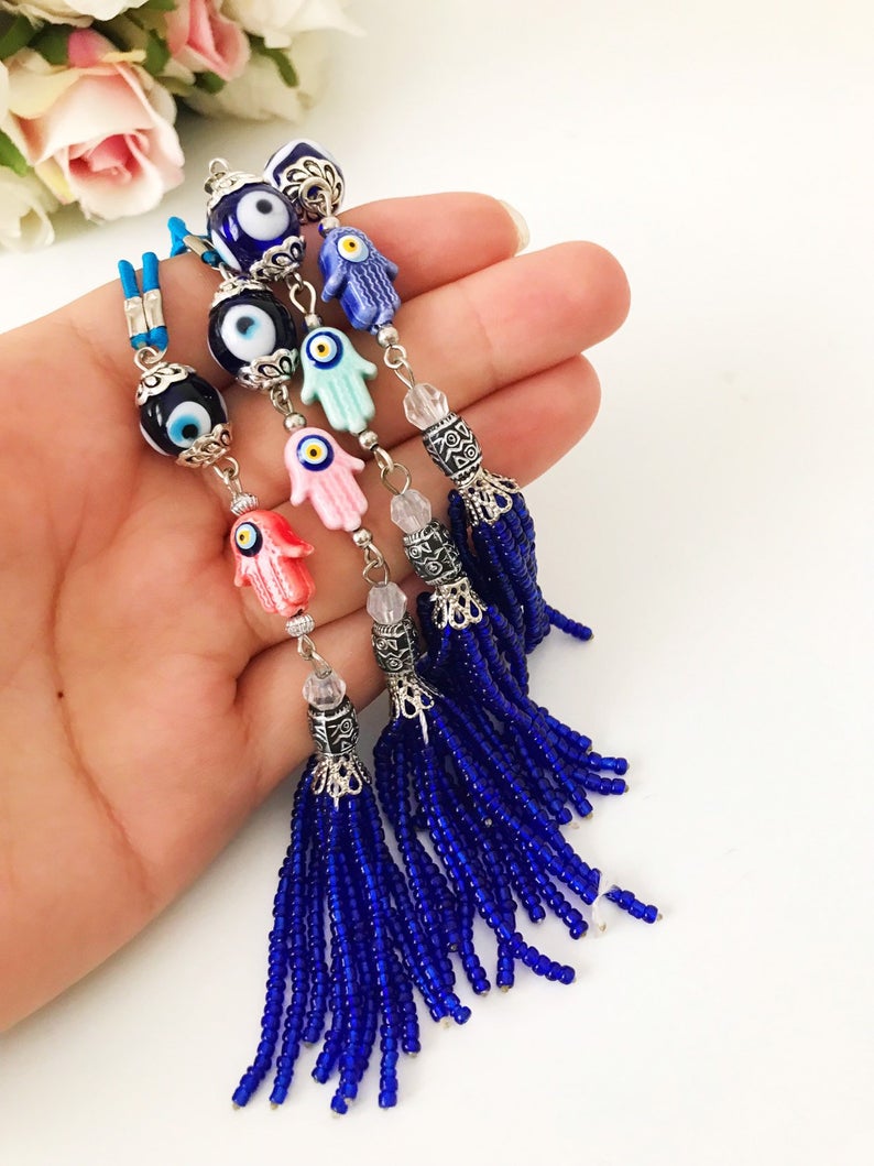 Handmade Hamsa hand evil eye rear mirror charm featuring colorful glass beads, hanging elegantly from a car's rearview mirror.