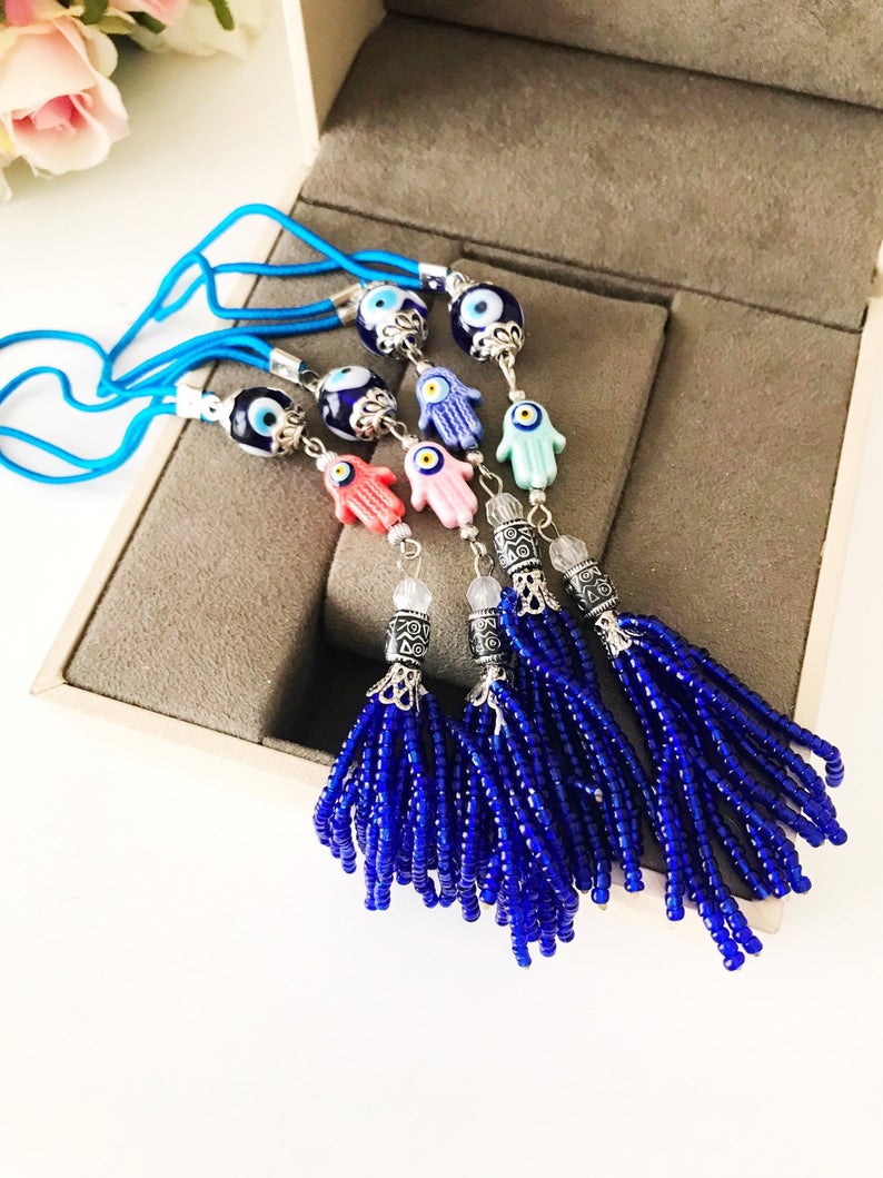 Handmade Hamsa hand evil eye rear mirror charm featuring colorful glass beads, hanging elegantly from a car's rearview mirror.