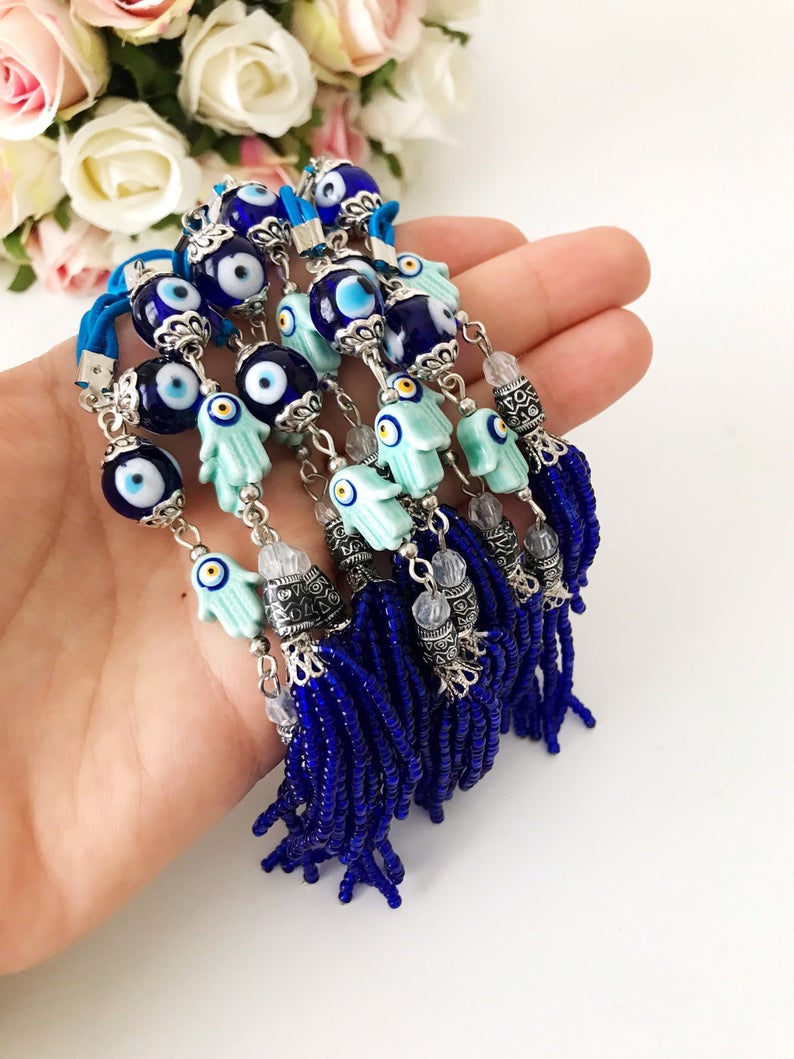 Handmade Hamsa hand evil eye rear mirror charm featuring colorful glass beads, hanging elegantly from a car's rearview mirror.