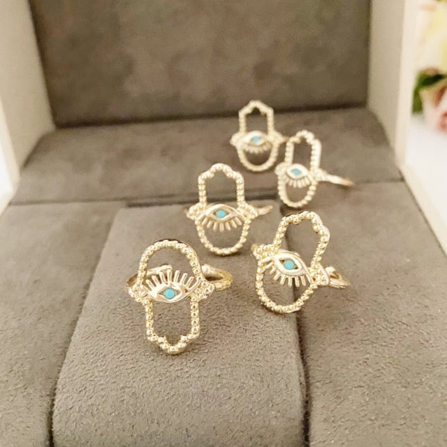 A beautiful adjustable gold Hamsa Hand Ring featuring an evil eye design, symbolizing protection and luck.