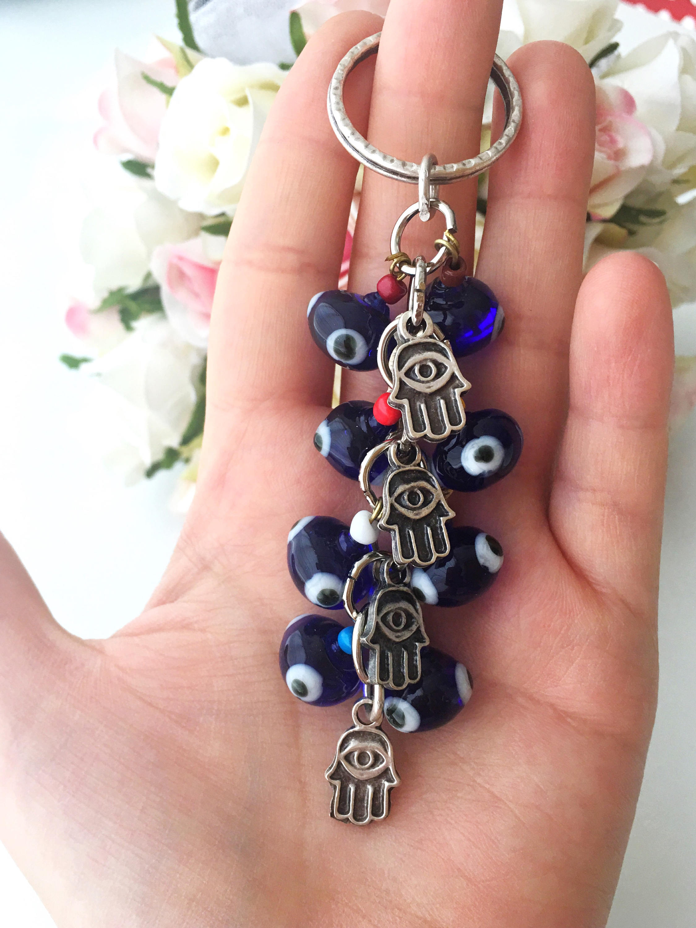 A beautifully crafted Hamsa keychain featuring a blue glass evil eye bead, symbolizing protection and good luck.
