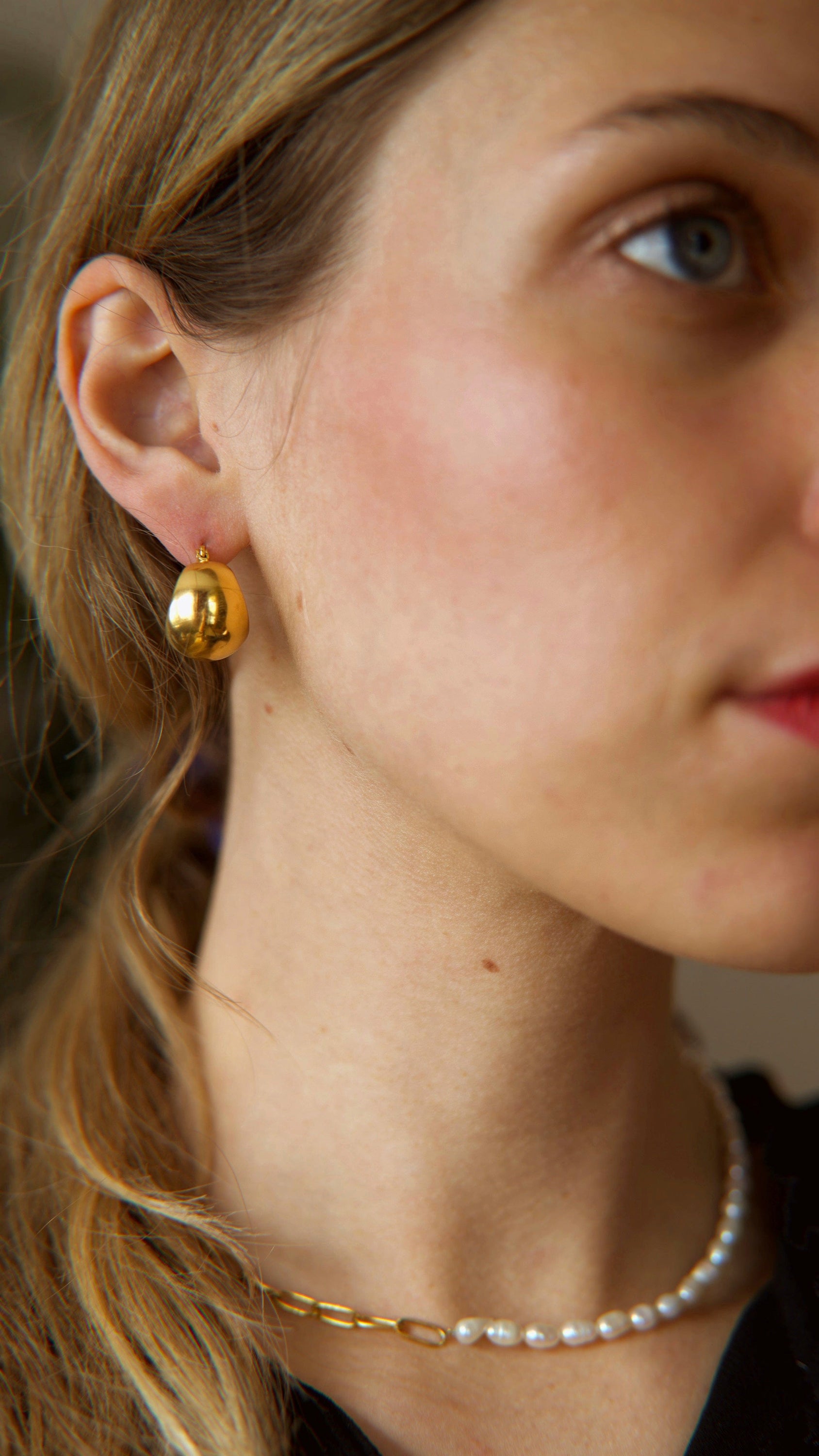 A pair of Hazel ball hoop earrings made from stainless steel with 18Kt yellow gold PVD plating, showcasing a unique and bold design.