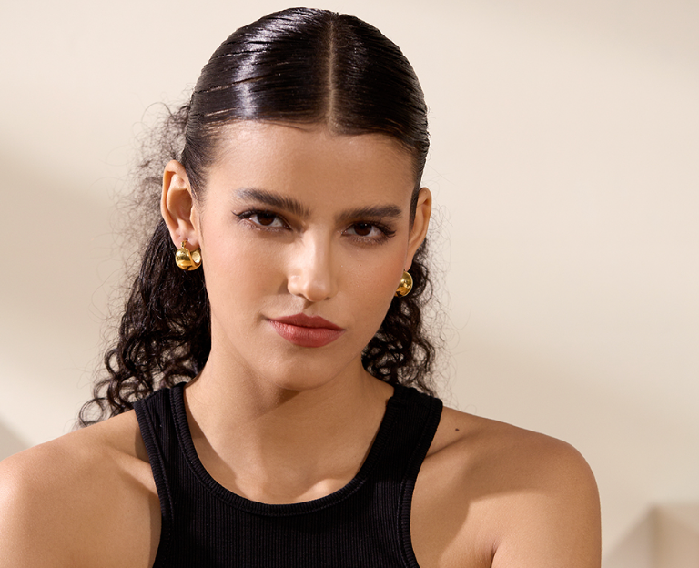 A pair of Hazel ball hoop earrings made from stainless steel with 18Kt yellow gold PVD plating, showcasing a unique and bold design.