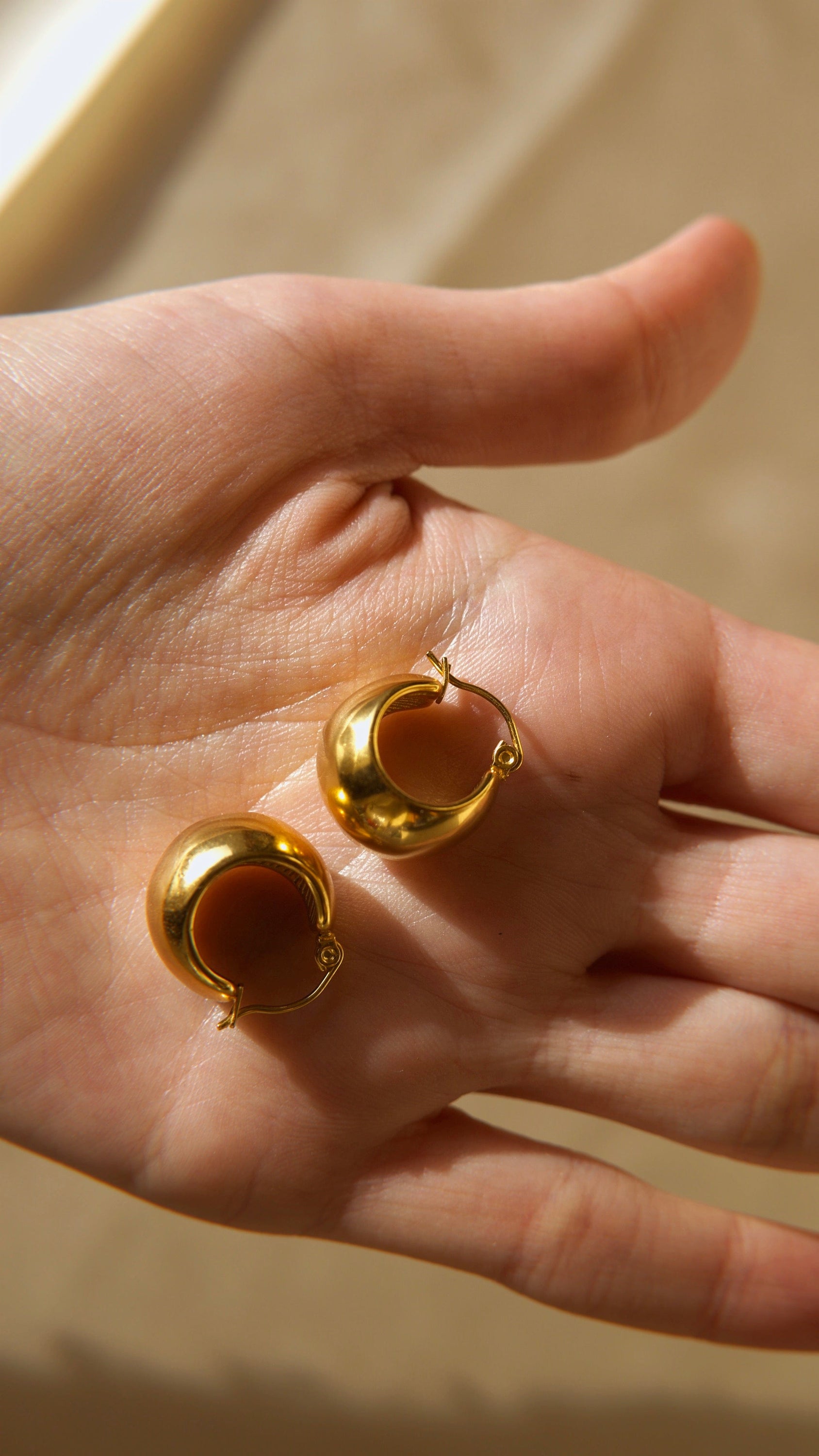 A pair of Hazel ball hoop earrings made from stainless steel with 18Kt yellow gold PVD plating, showcasing a unique and bold design.