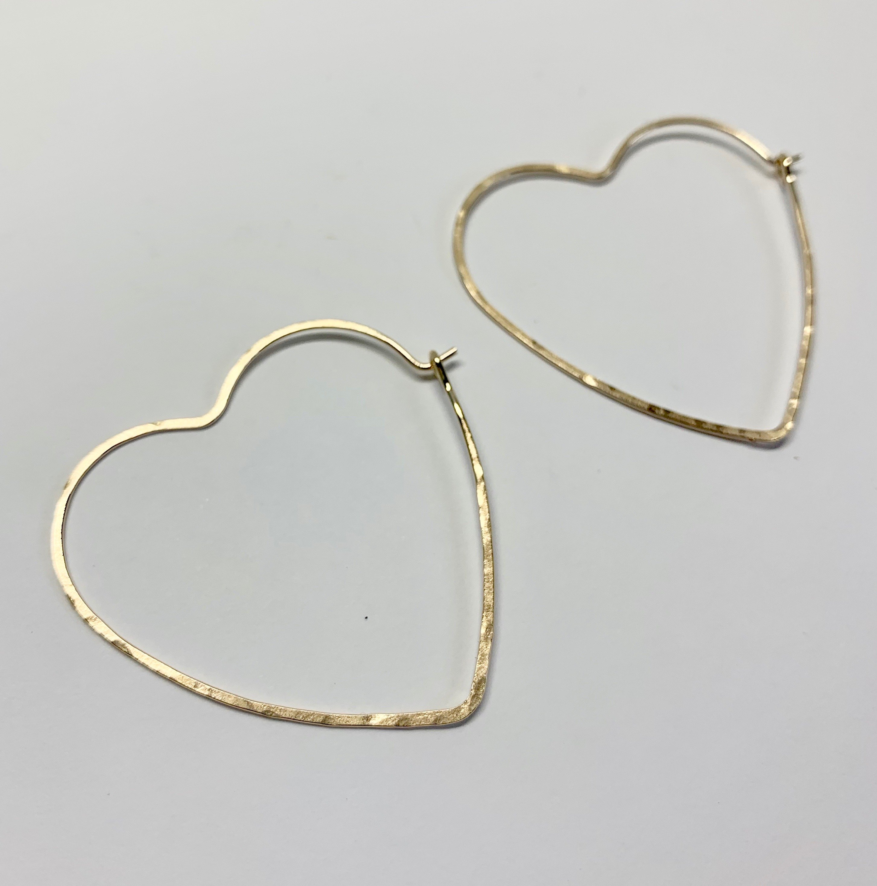 Large heart-shaped hoops made from 20 gauge wire, featuring a hammered texture for shine, available in silver, yellow gold fill, and rose gold fill.