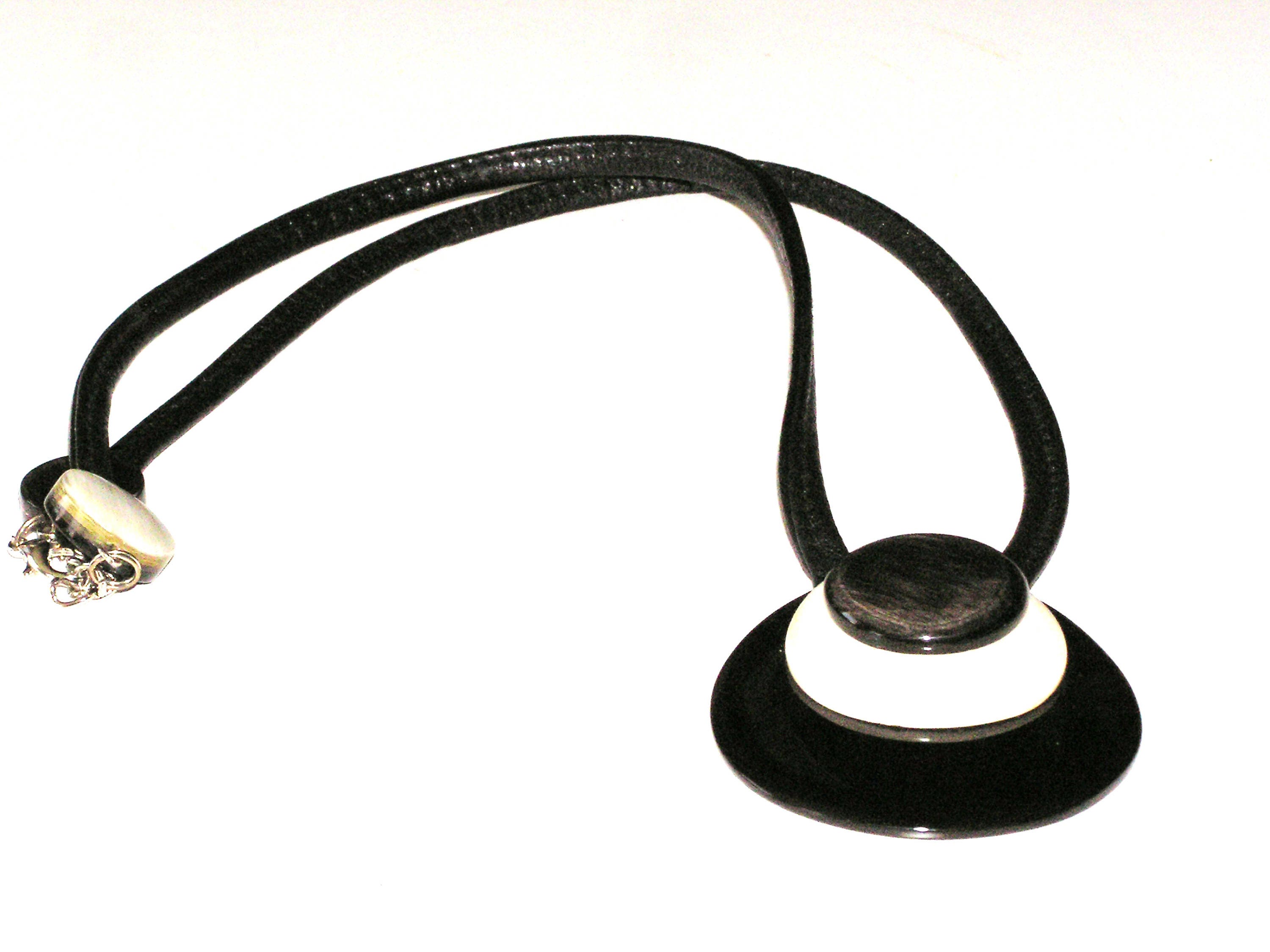 Handmade drop-shaped horn pendant on a leather cord, showcasing unique black and white patterns.