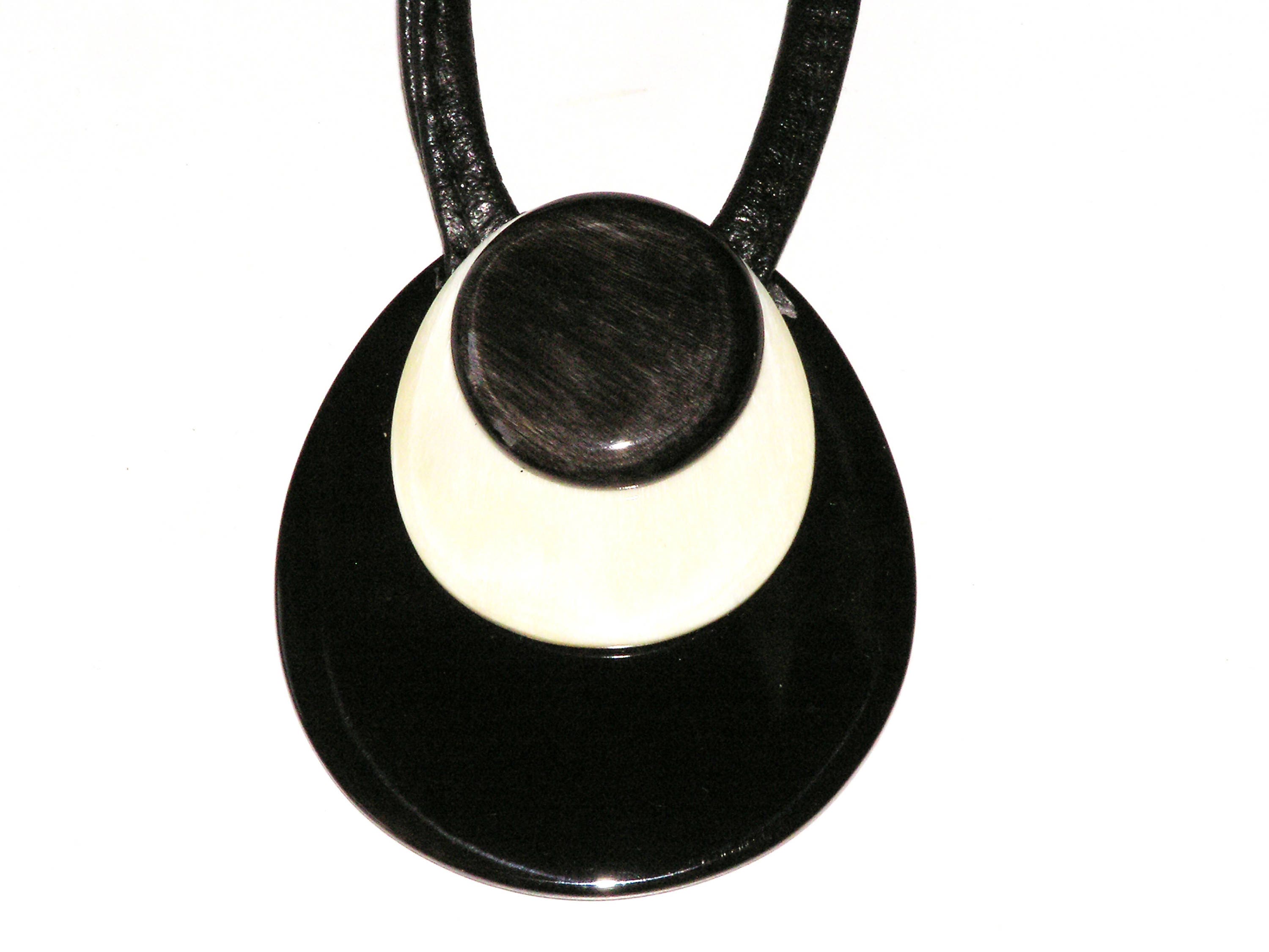 Handmade drop-shaped horn pendant on a leather cord, showcasing unique black and white patterns.