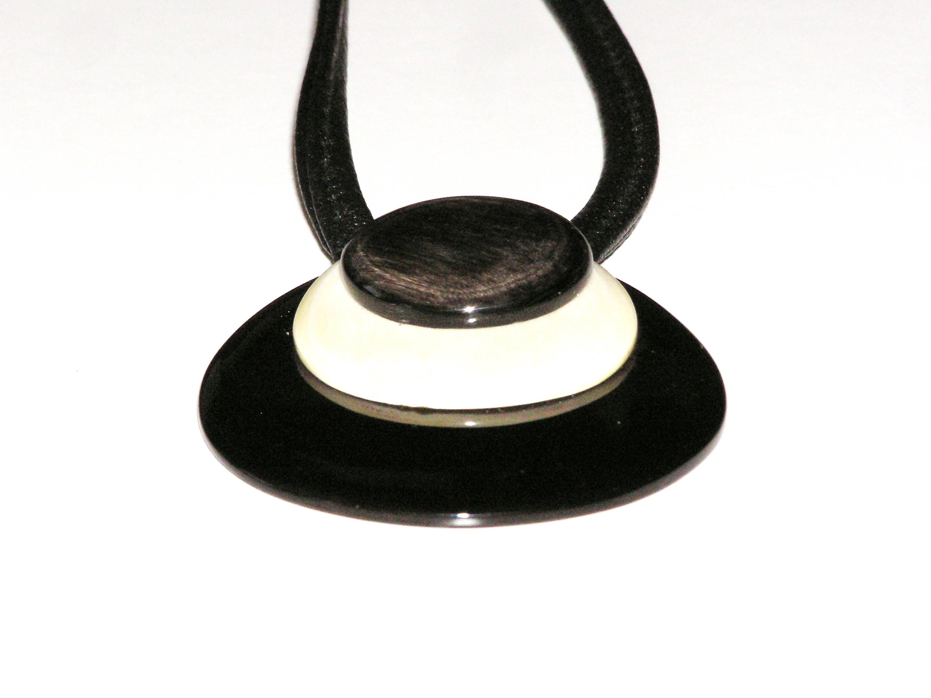 Handmade drop-shaped horn pendant on a leather cord, showcasing unique black and white patterns.