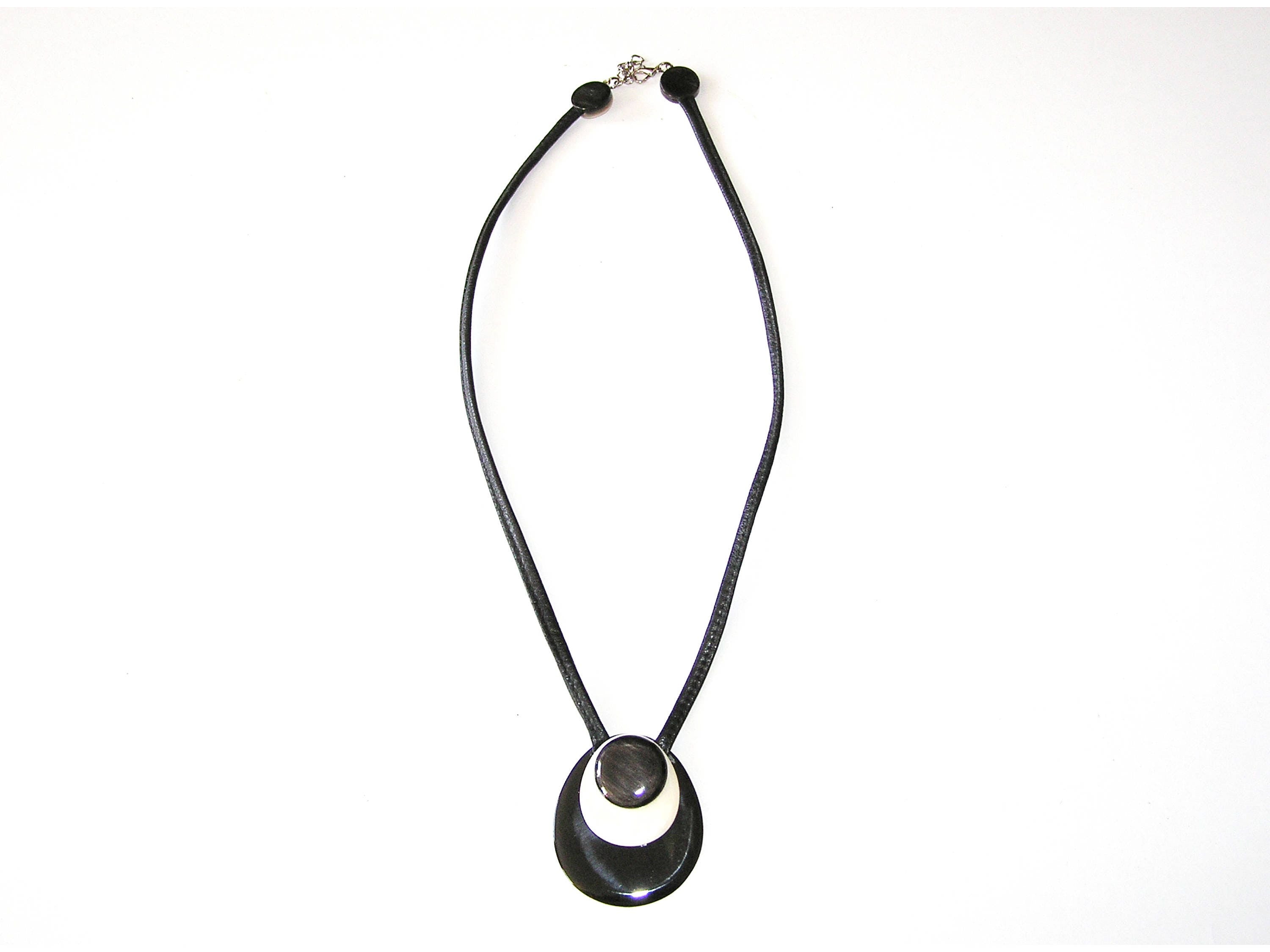 Handmade drop-shaped horn pendant on a leather cord, showcasing unique black and white patterns.