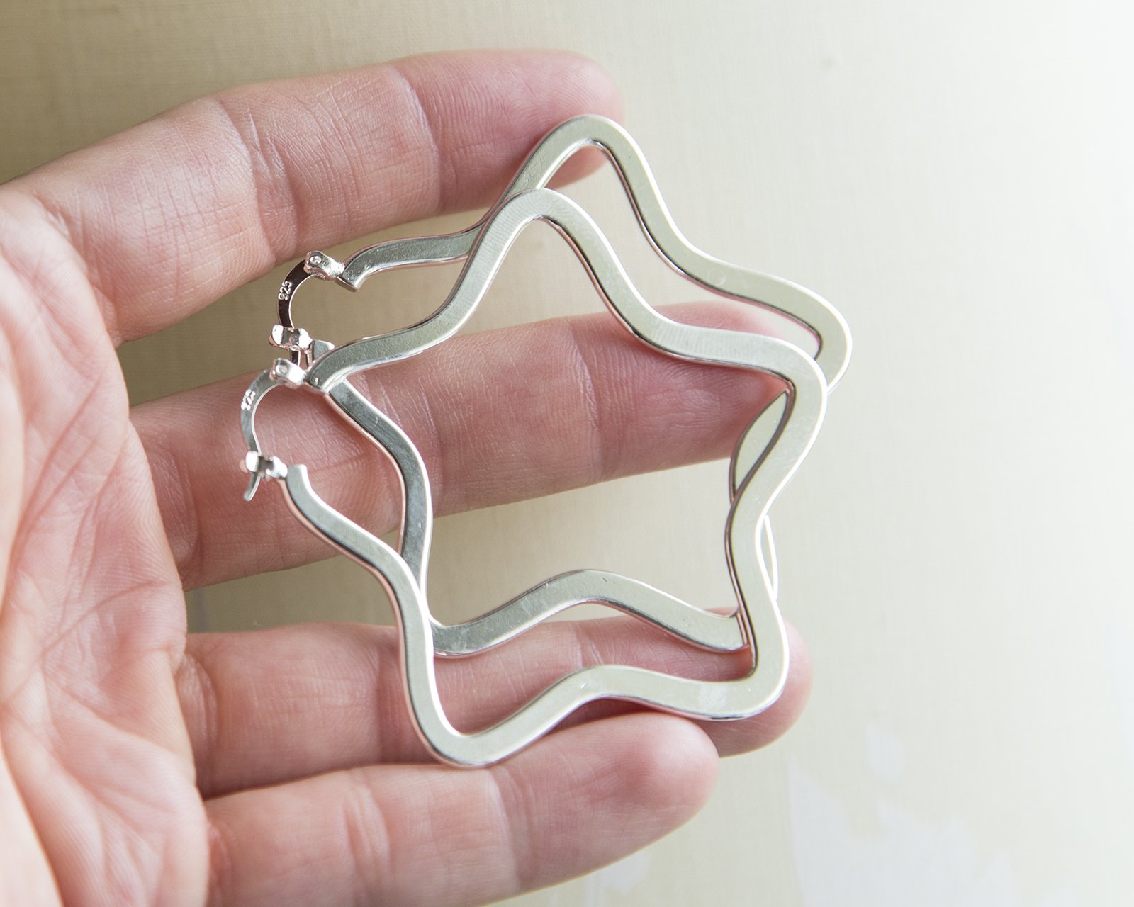 A pair of large silver star hoop earrings, showcasing a unique star design with a shiny finish, perfect for gifting.