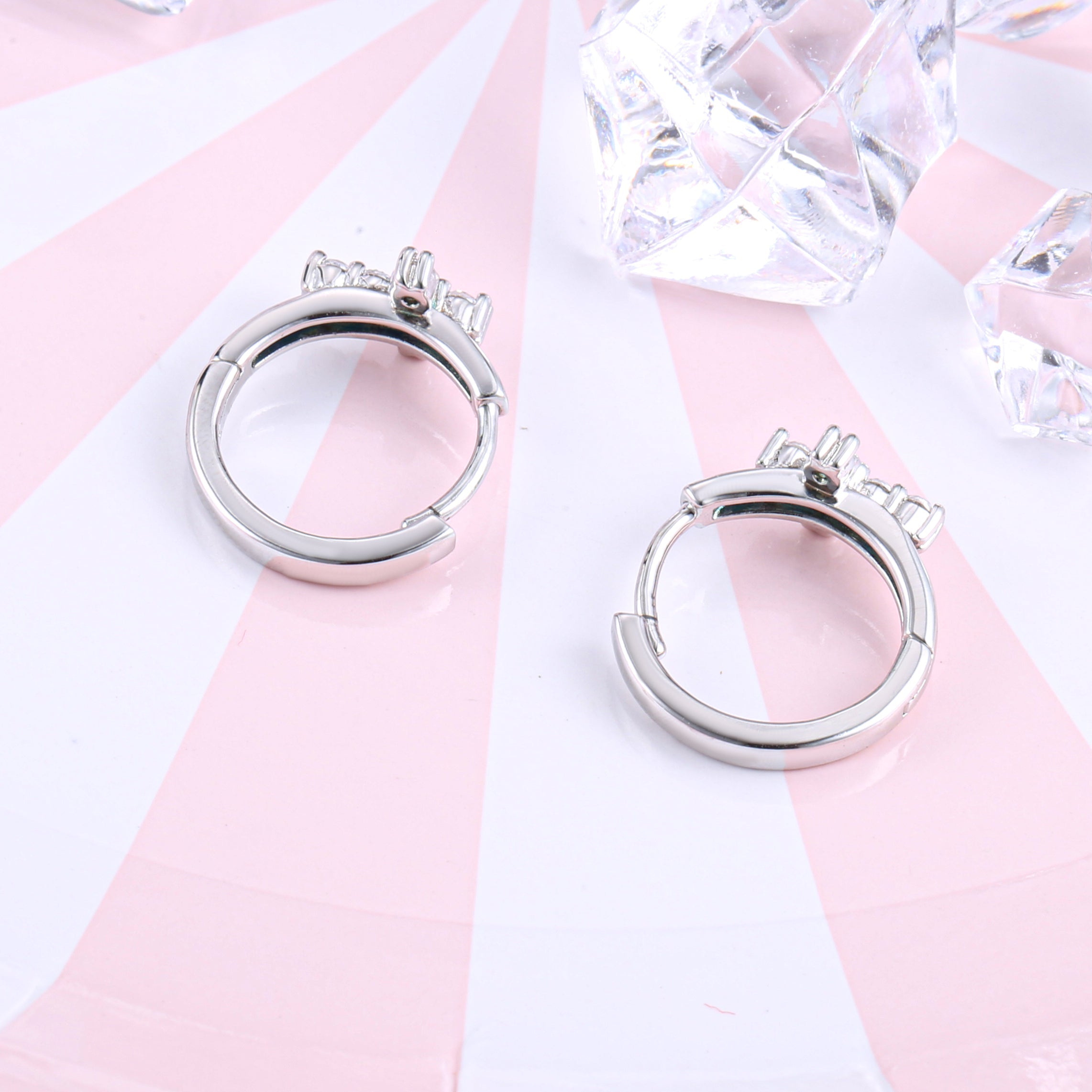 A pair of Huggie hoop cross earrings made from 925 sterling silver with white gold finish and white sapphire stones.