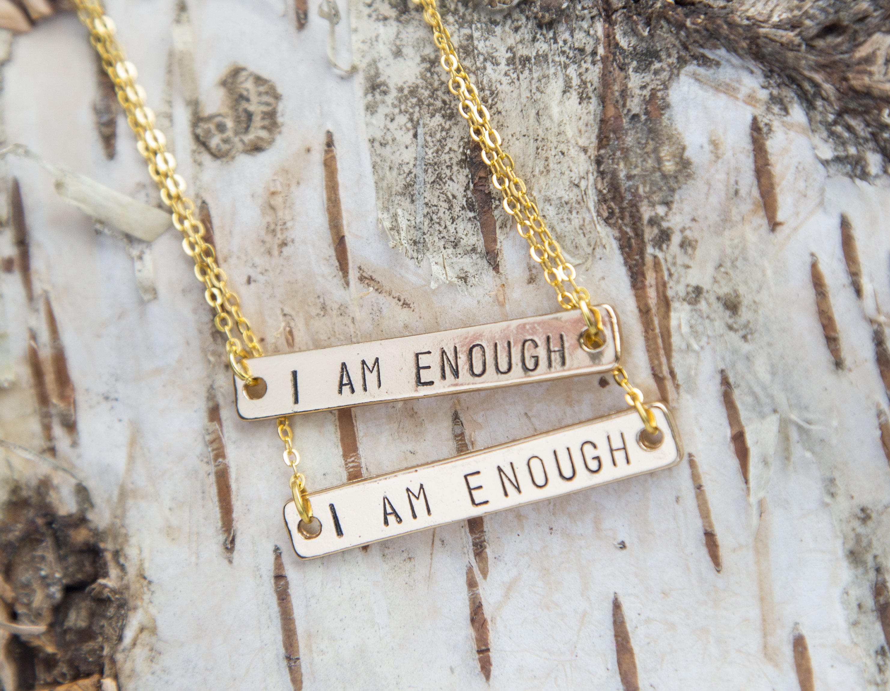 Hand-stamped golden bar necklace with the phrase 'I Am Enough', showcasing its unique design and craftsmanship.