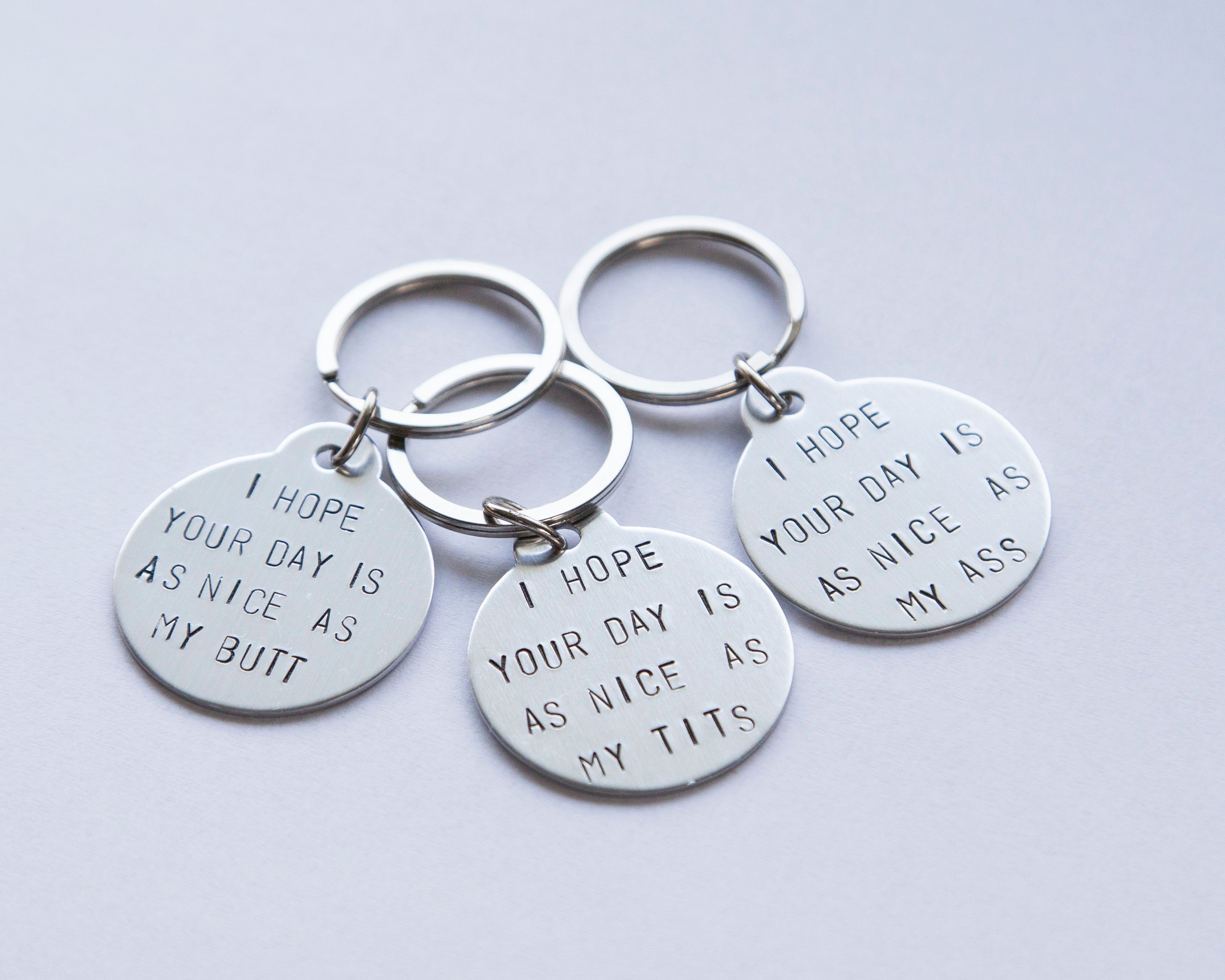 A humorous keyring with the phrase 'I hope your day is as nice as my butt', featuring a stainless steel keyring and lightweight aluminum tag.