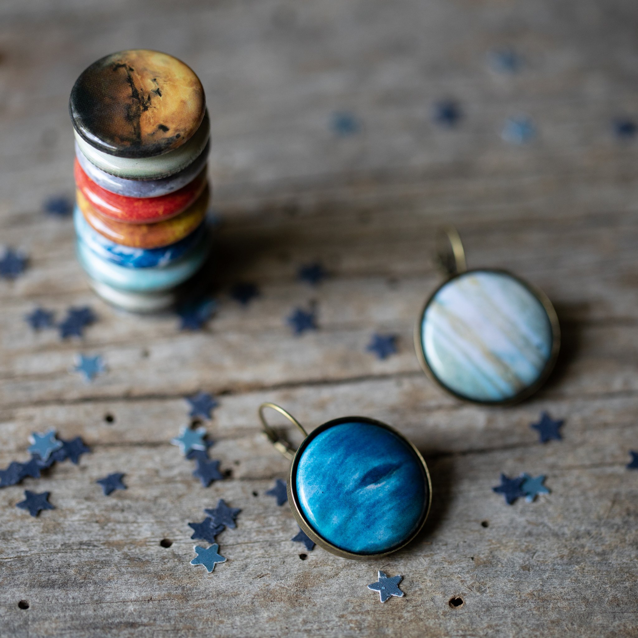 A pair of interchangeable solar system earrings featuring 8 planets, the Moon, and the Sun, available in silver and bronze tones.