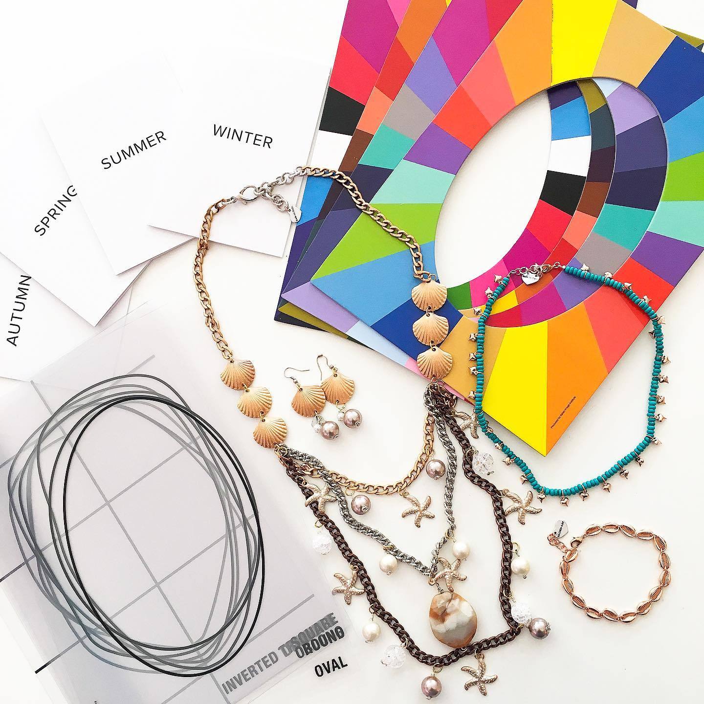 A woman participating in an online jewelry styling session, showcasing various jewelry pieces and accessories, with a laptop in front of her.