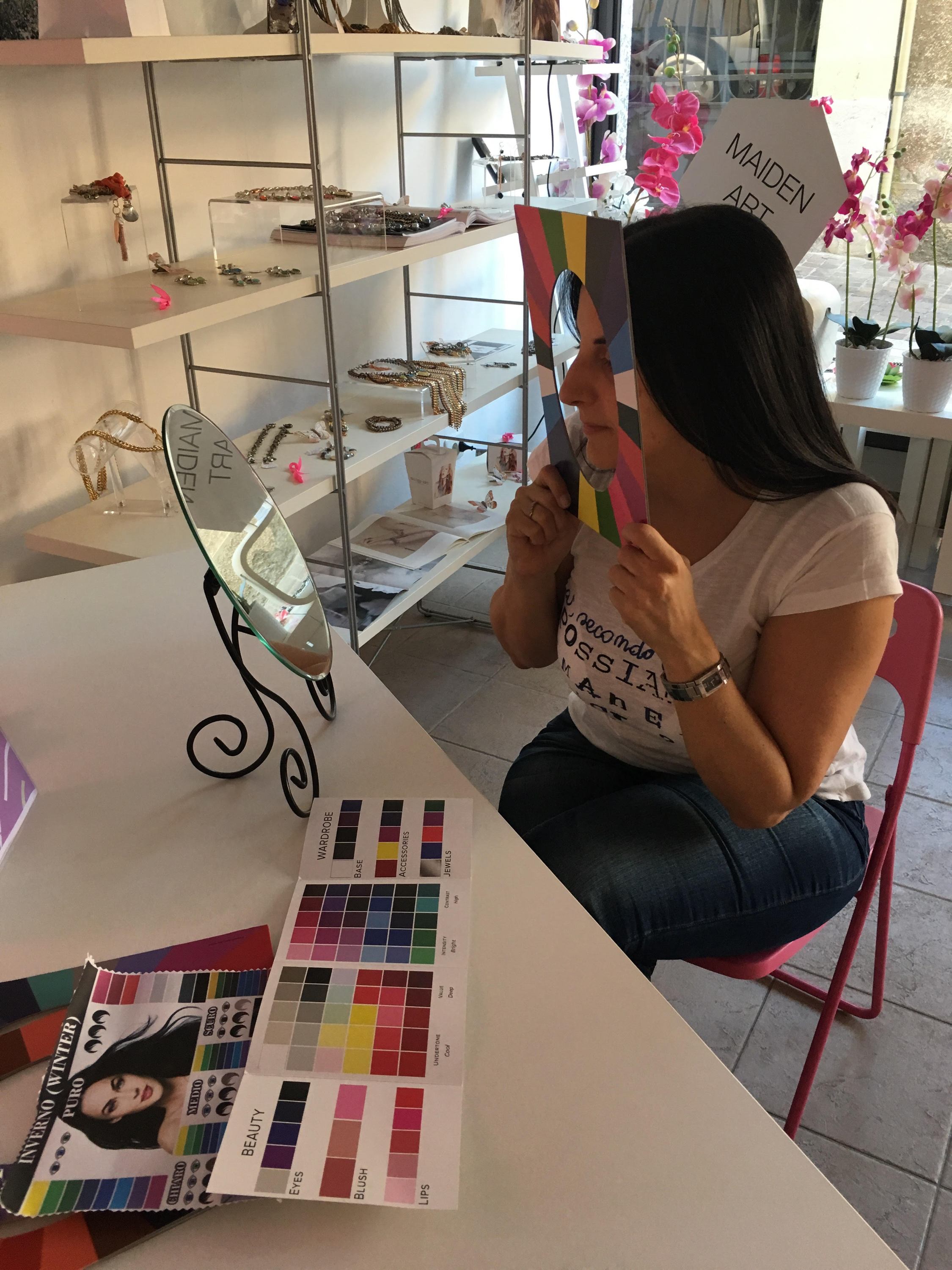 A woman participating in an online jewelry styling session, showcasing various jewelry pieces and accessories, with a laptop in front of her.