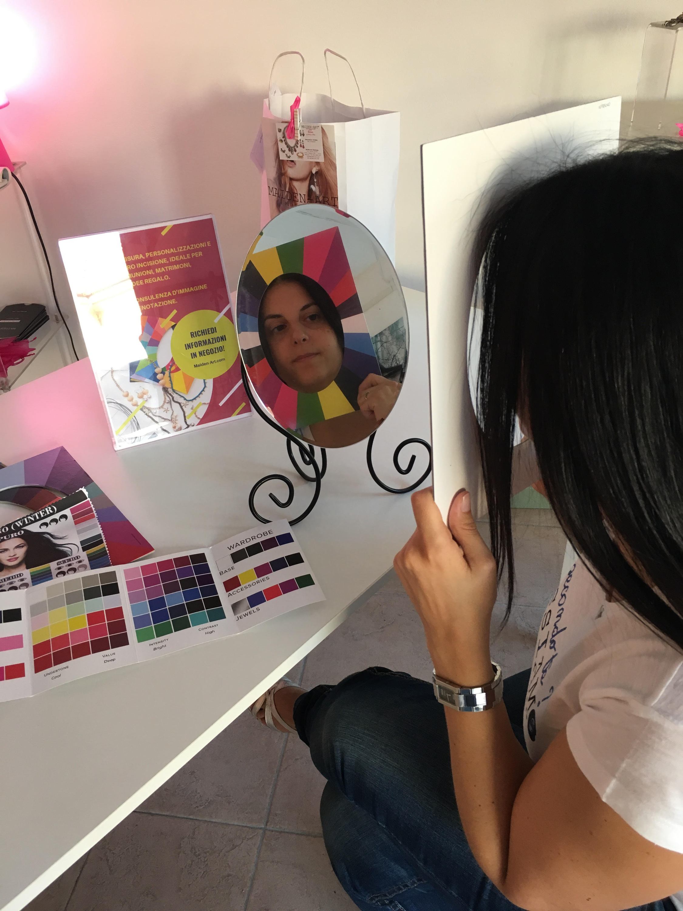 A woman participating in an online jewelry styling session, showcasing various jewelry pieces and accessories, with a laptop in front of her.