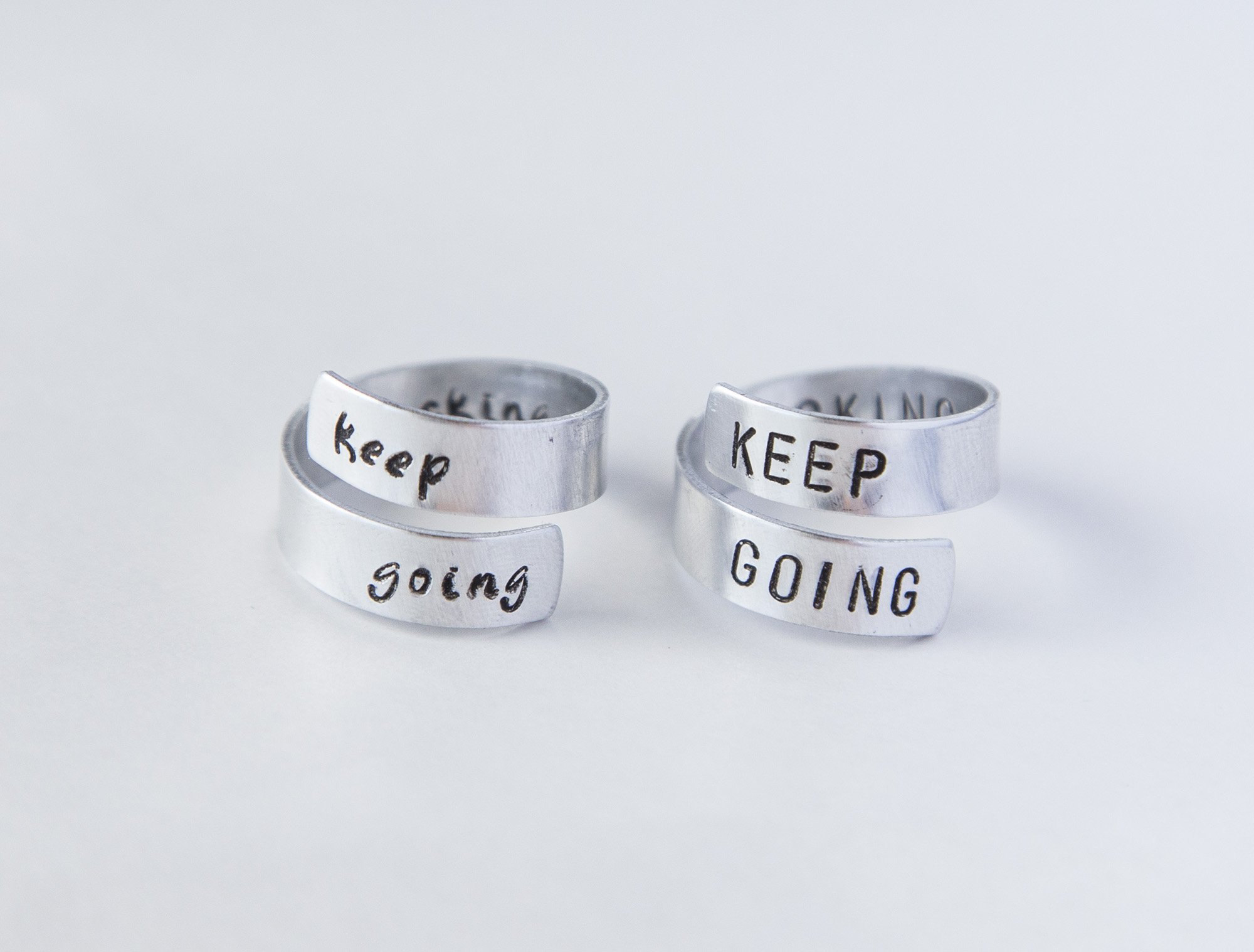 Keep Fucking Going Twist Ring made of aluminum, featuring hand-stamped motivational text, adjustable size, and unique handmade design.