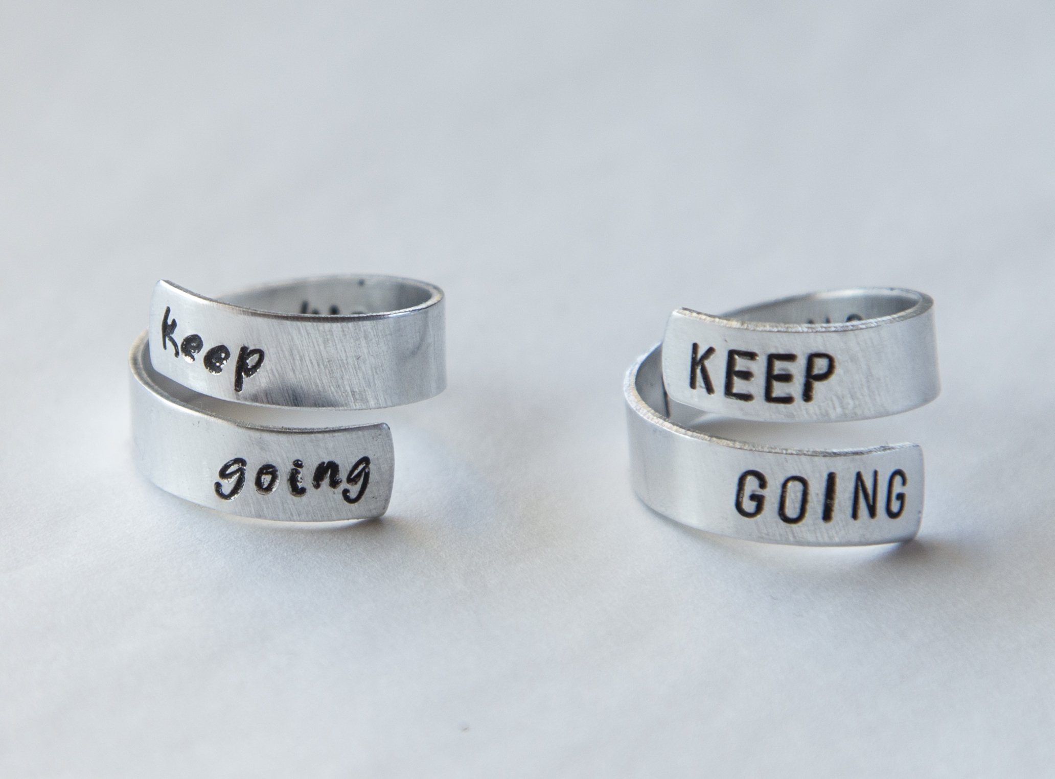 Keep Fucking Going Twist Ring made of aluminum, featuring hand-stamped motivational text, adjustable size, and unique handmade design.