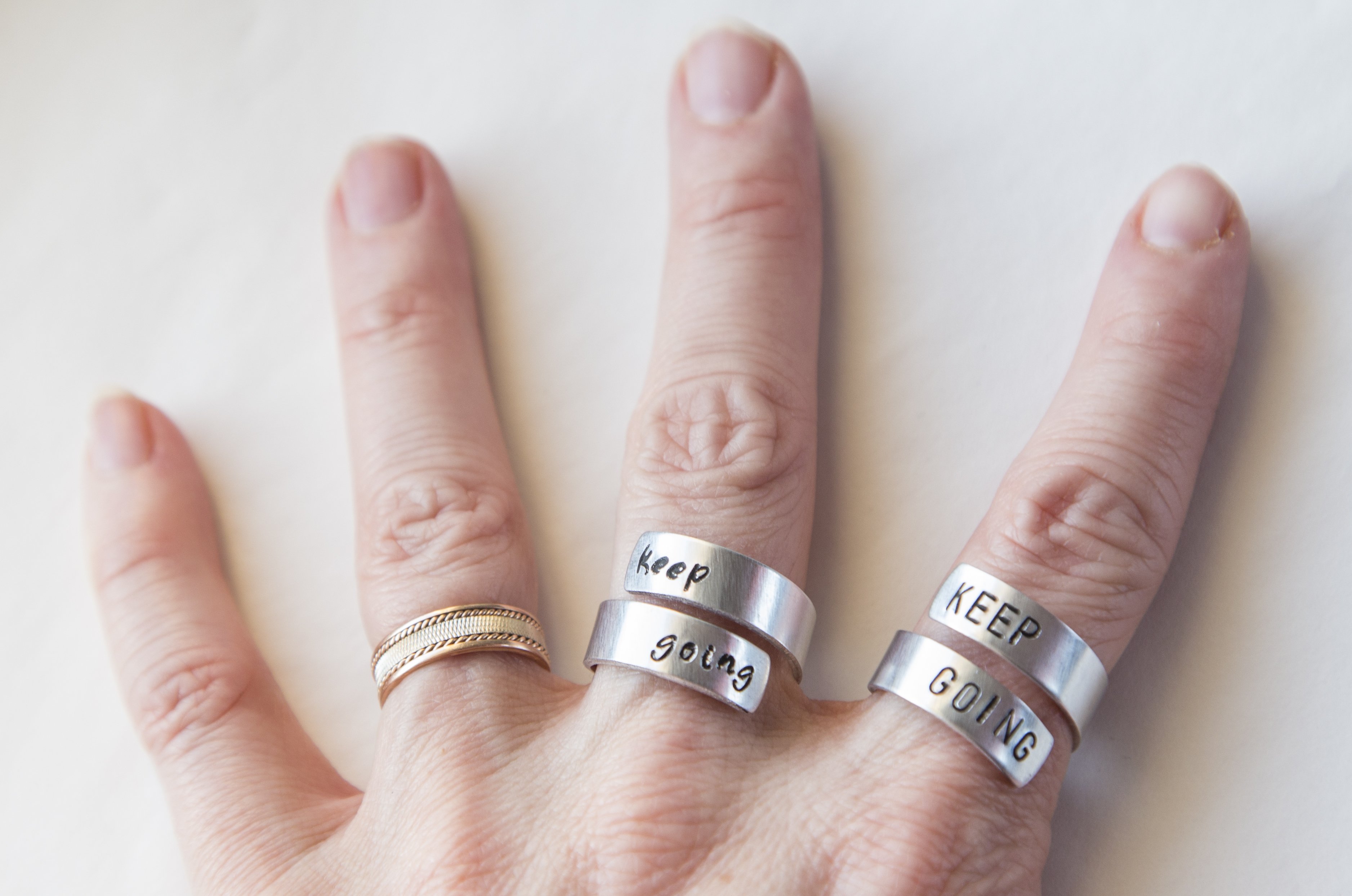 Keep Fucking Going Twist Ring made of aluminum, featuring hand-stamped motivational text, adjustable size, and unique handmade design.