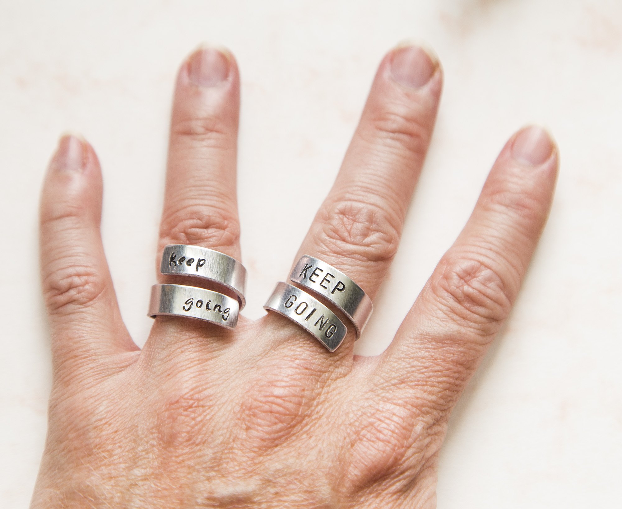 Keep Fucking Going Twist Ring made of aluminum, featuring hand-stamped motivational text, adjustable size, and unique handmade design.