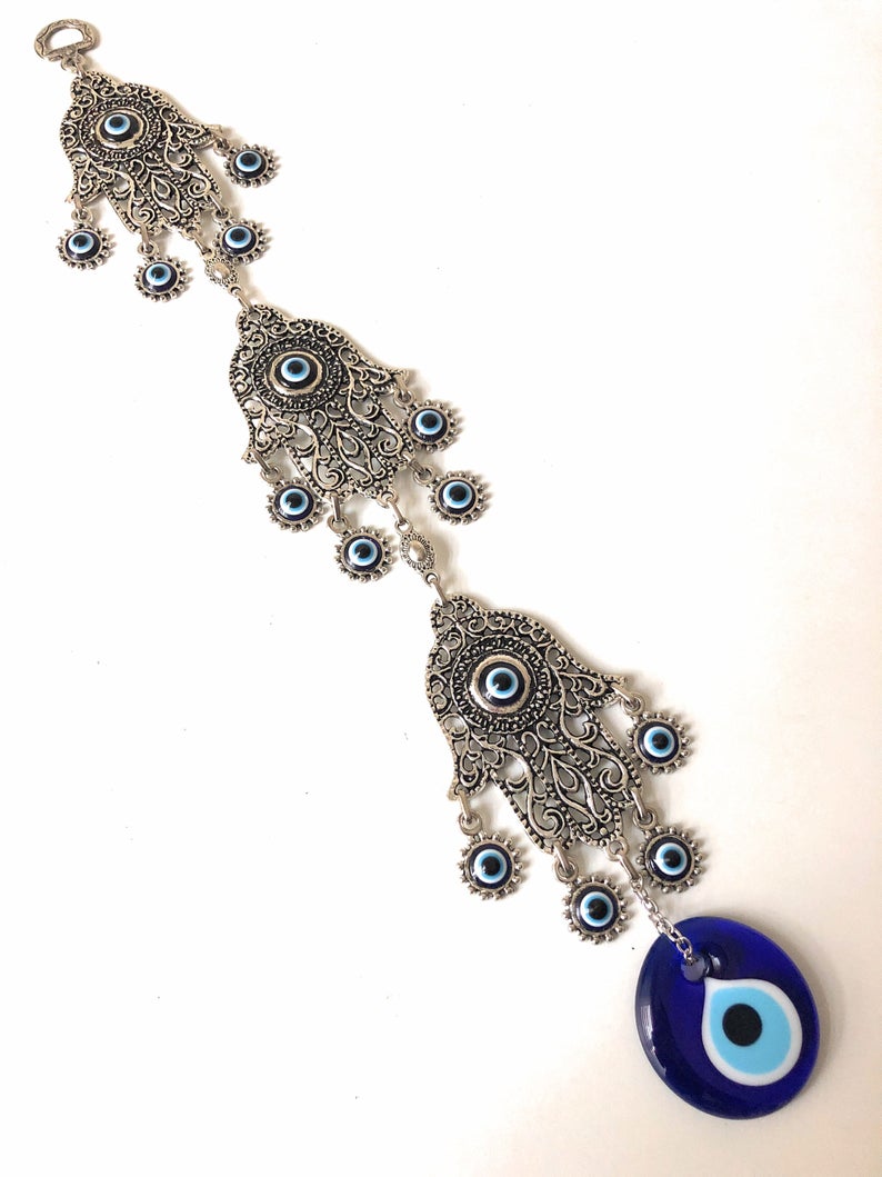 Large Evil Eye Wall Hanging featuring blue evil eye bead, hamsa hand, and lucky elephant designs, crafted from metal for home decor.