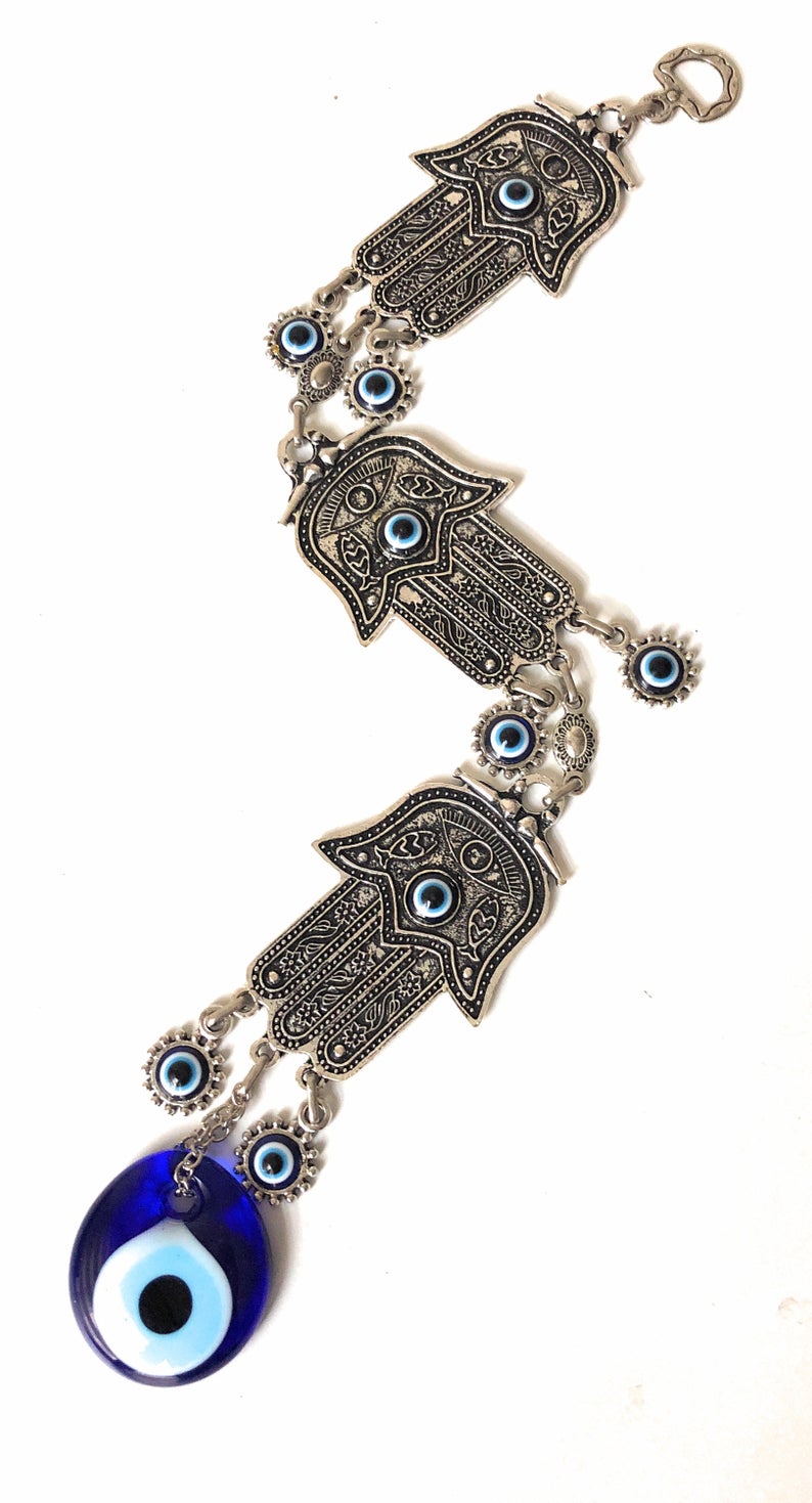 Large Evil Eye Wall Hanging featuring blue evil eye bead, hamsa hand, and lucky elephant designs, crafted from metal for home decor.