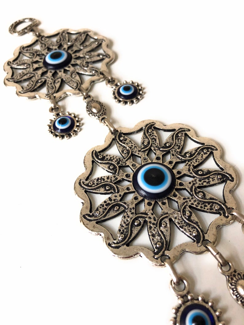 Large Evil Eye Wall Hanging featuring blue evil eye bead, hamsa hand, and lucky elephant designs, crafted from metal for home decor.