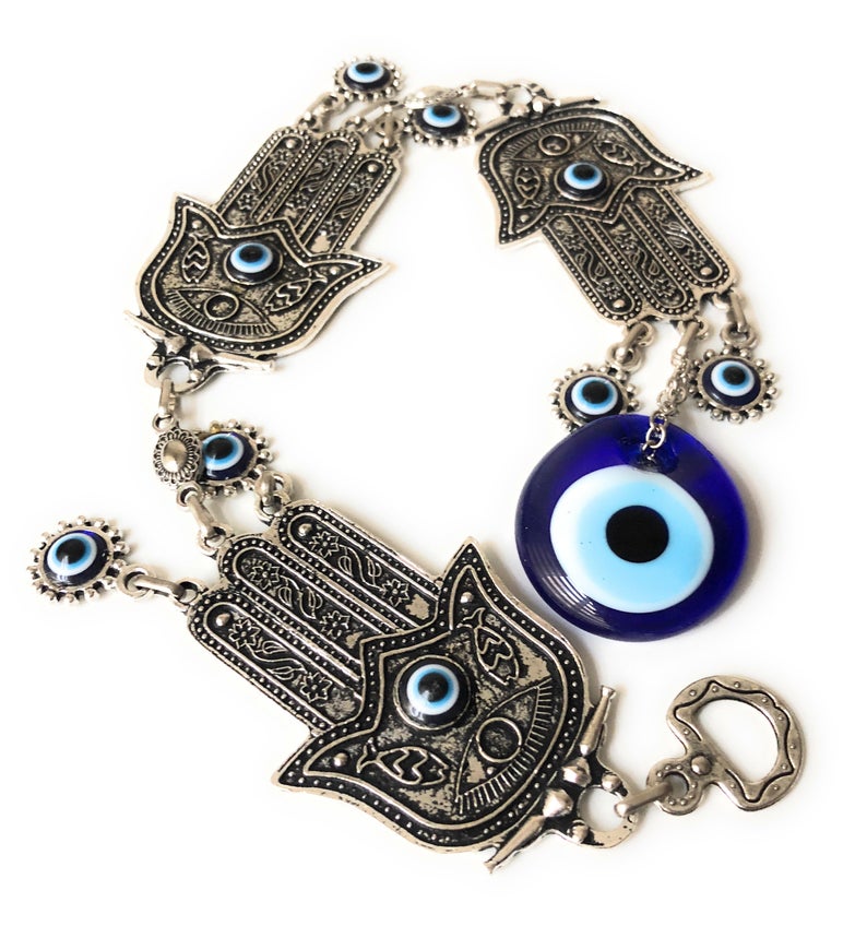 Large Evil Eye Wall Hanging featuring blue evil eye bead, hamsa hand, and lucky elephant designs, crafted from metal for home decor.