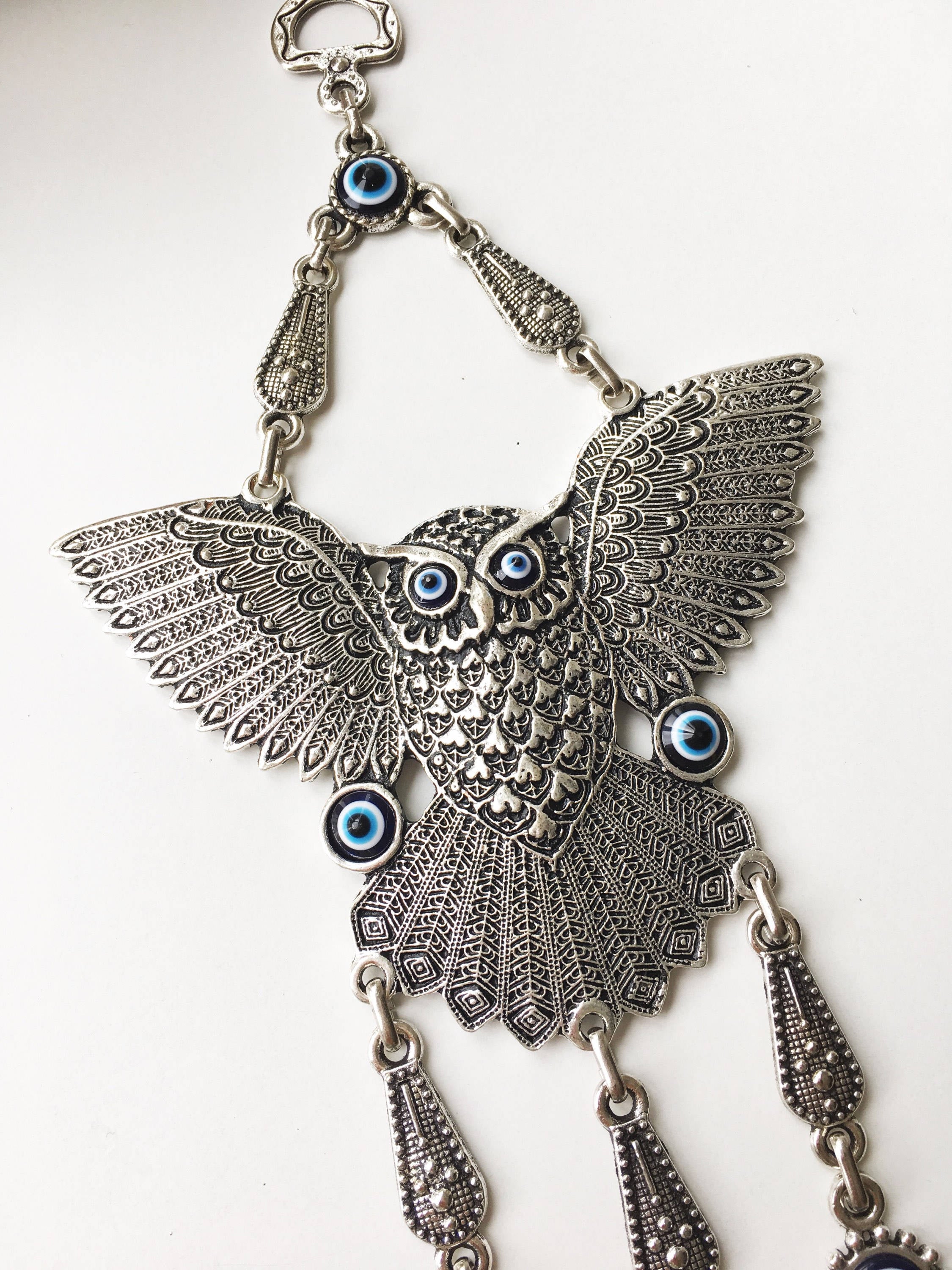 A beautifully handcrafted Large Owl Evil Eye Wall Hanging featuring a vibrant glass evil eye bead and intricate metal charm details.