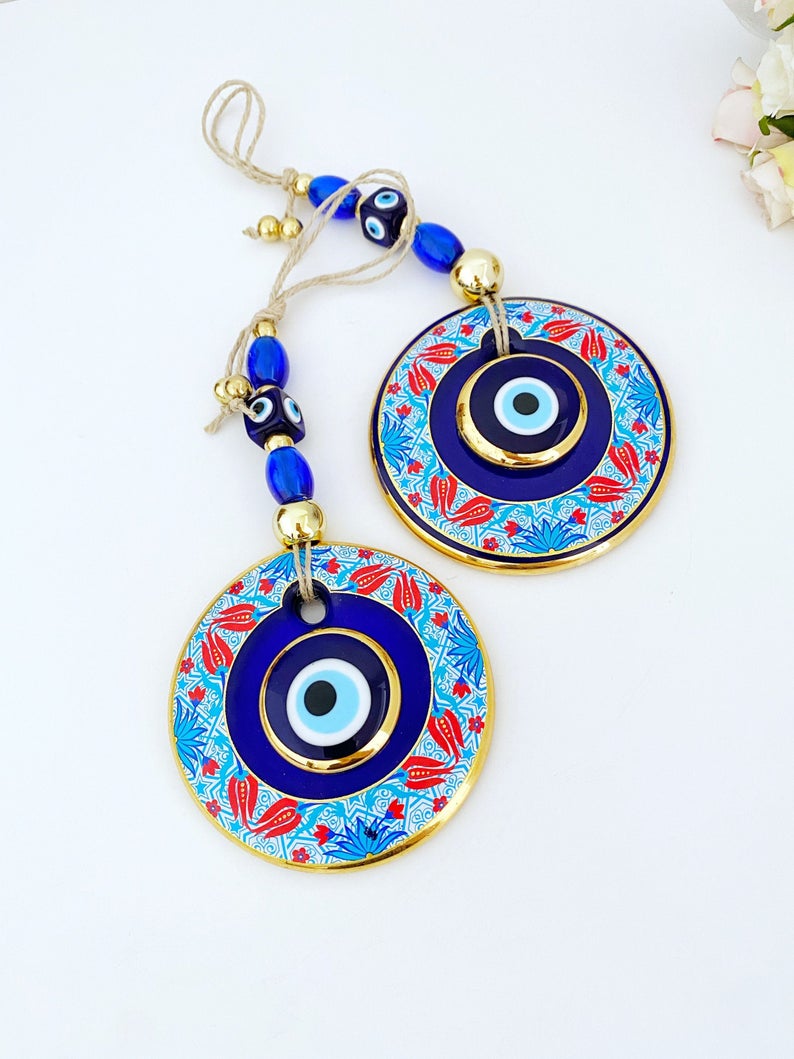 A beautifully handpainted Larger Evil Eye Wall Hanging featuring a large glass round evil eye and smaller evil eyes, perfect for home decor.