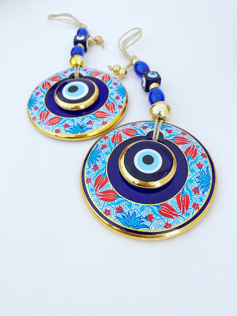 A beautifully handpainted Larger Evil Eye Wall Hanging featuring a large glass round evil eye and smaller evil eyes, perfect for home decor.