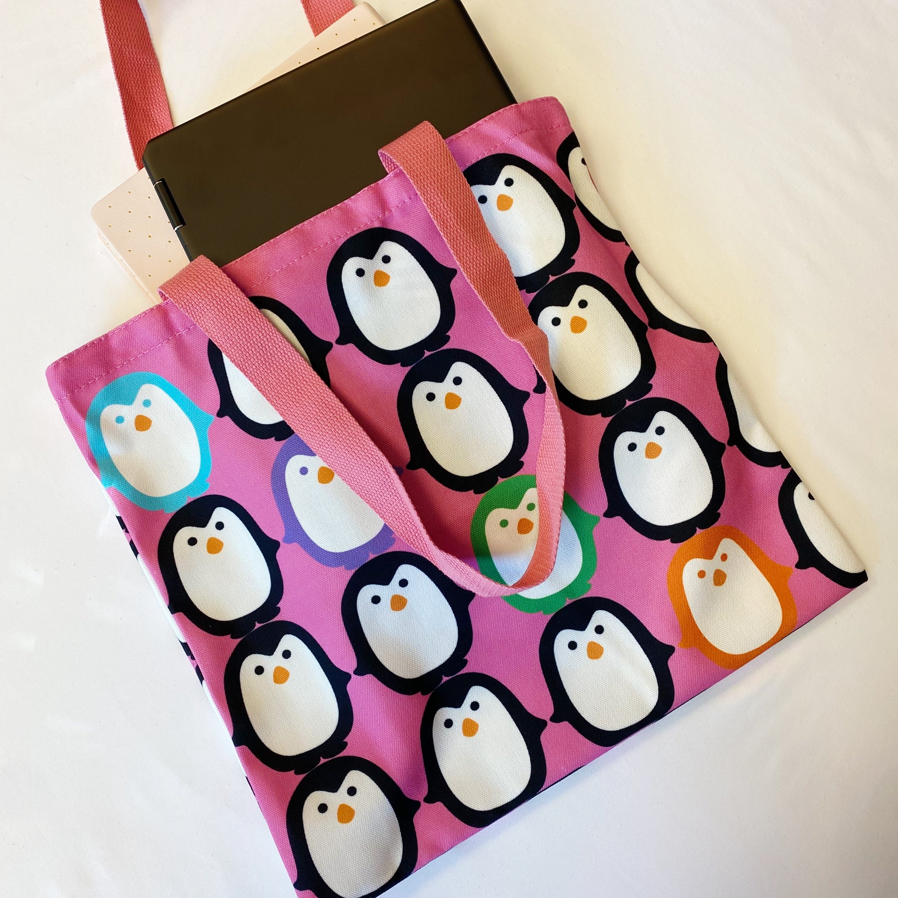 A colorful canvas tote bag featuring a playful penguin design, perfect for eco-conscious shoppers.