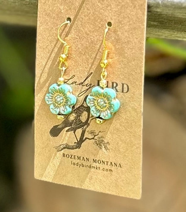 Light turquoise Czech glass wild rose flower earrings with gold etching, showcasing intricate design and vibrant color.
