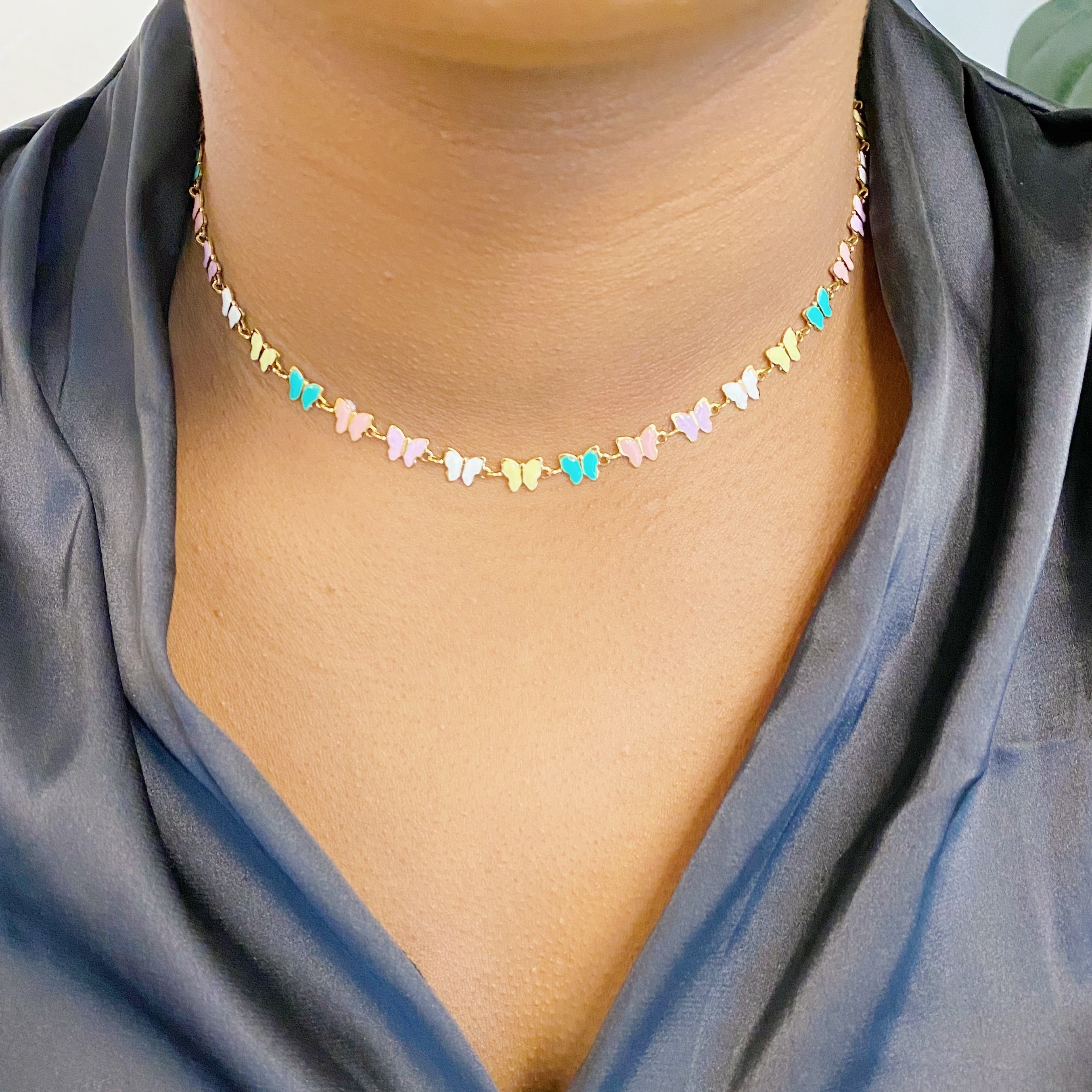 Linked Butterflies Necklace featuring pastel butterflies and a solid gold reversible side, crafted from gold plated stainless steel.