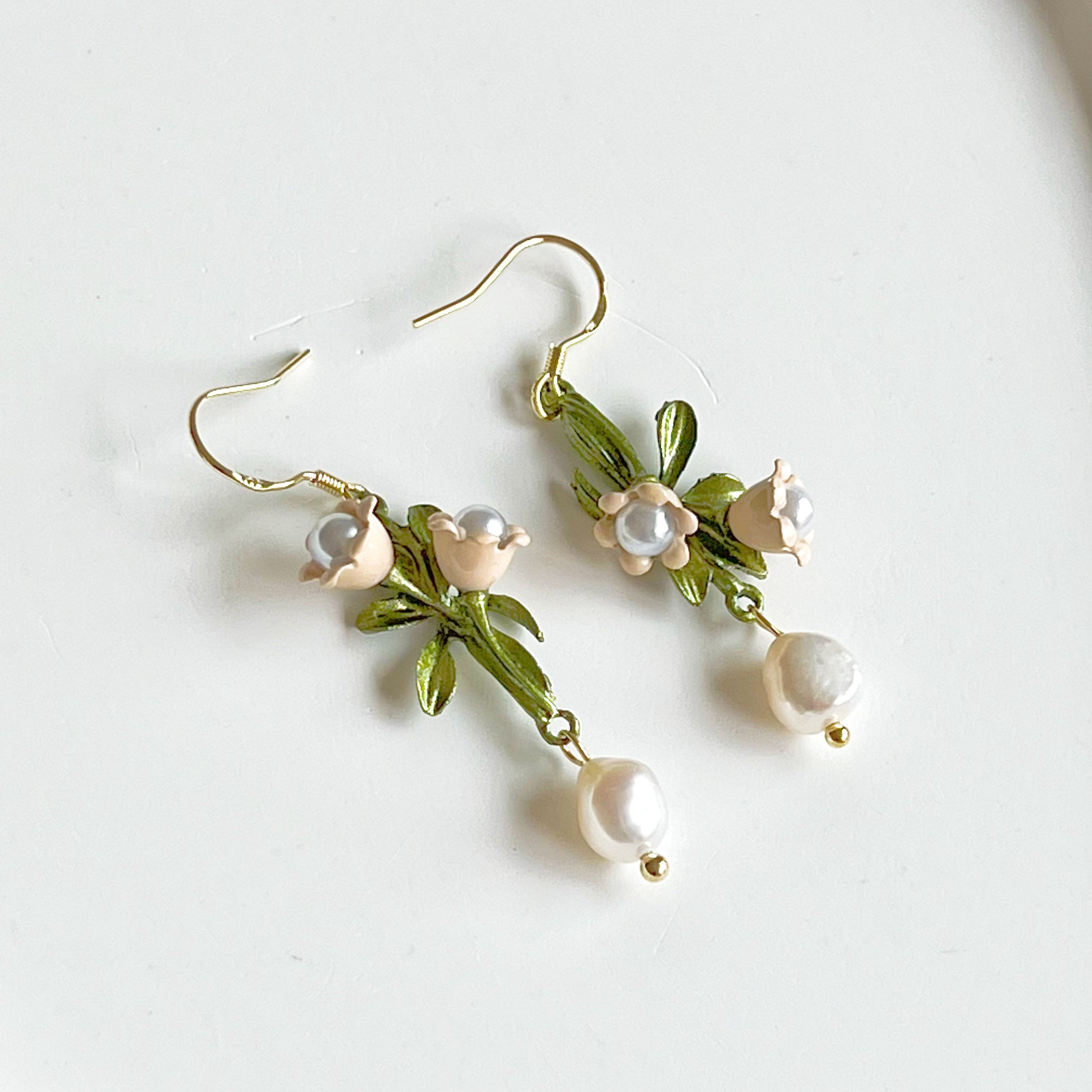 Elegant Little White Bell Flower Earrings with freshwater pearl drops, showcasing delicate floral design and green leaves.