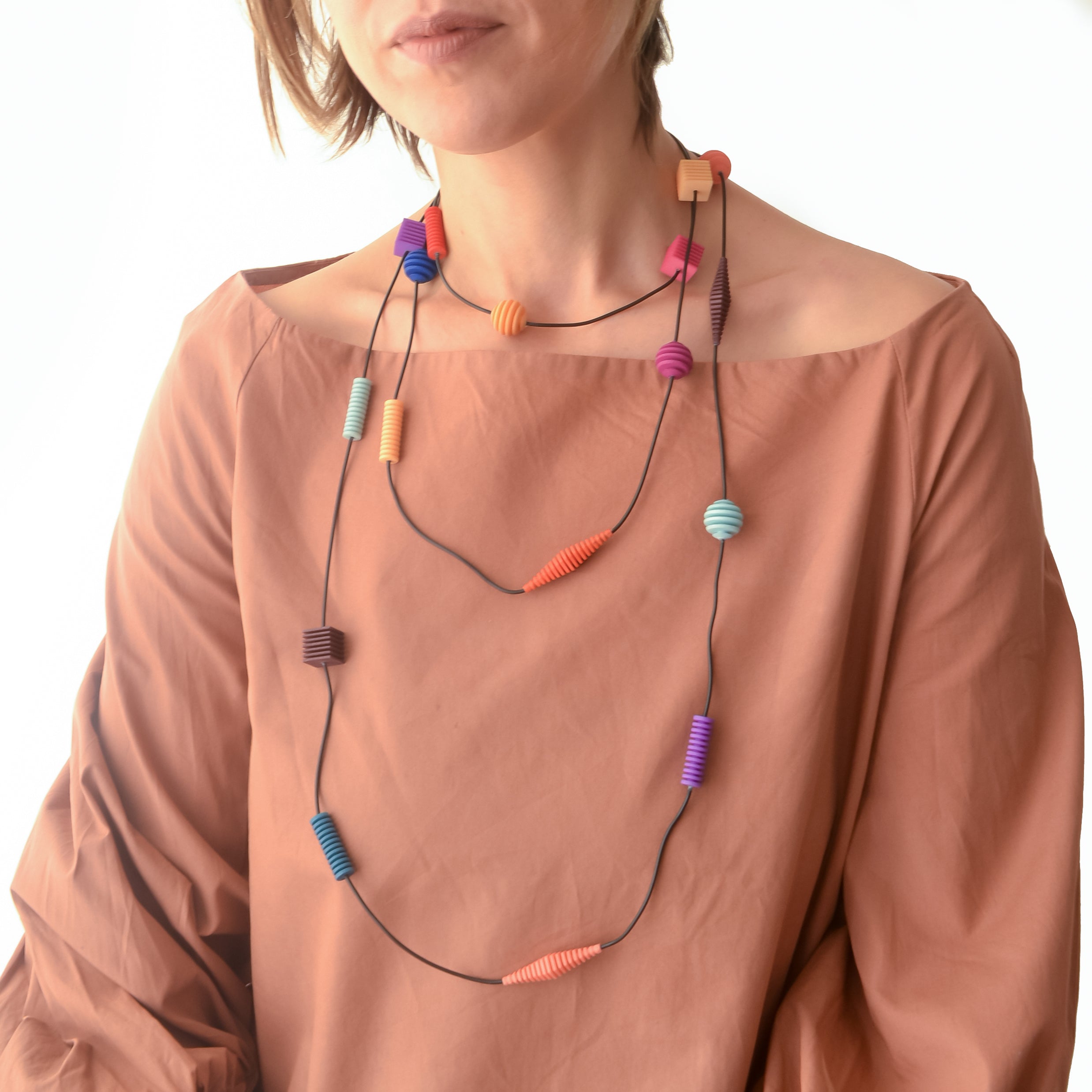Long Beaded Optical Necklace featuring vibrant hand-dyed beads in geometric shapes, perfect for stylish outfits.
