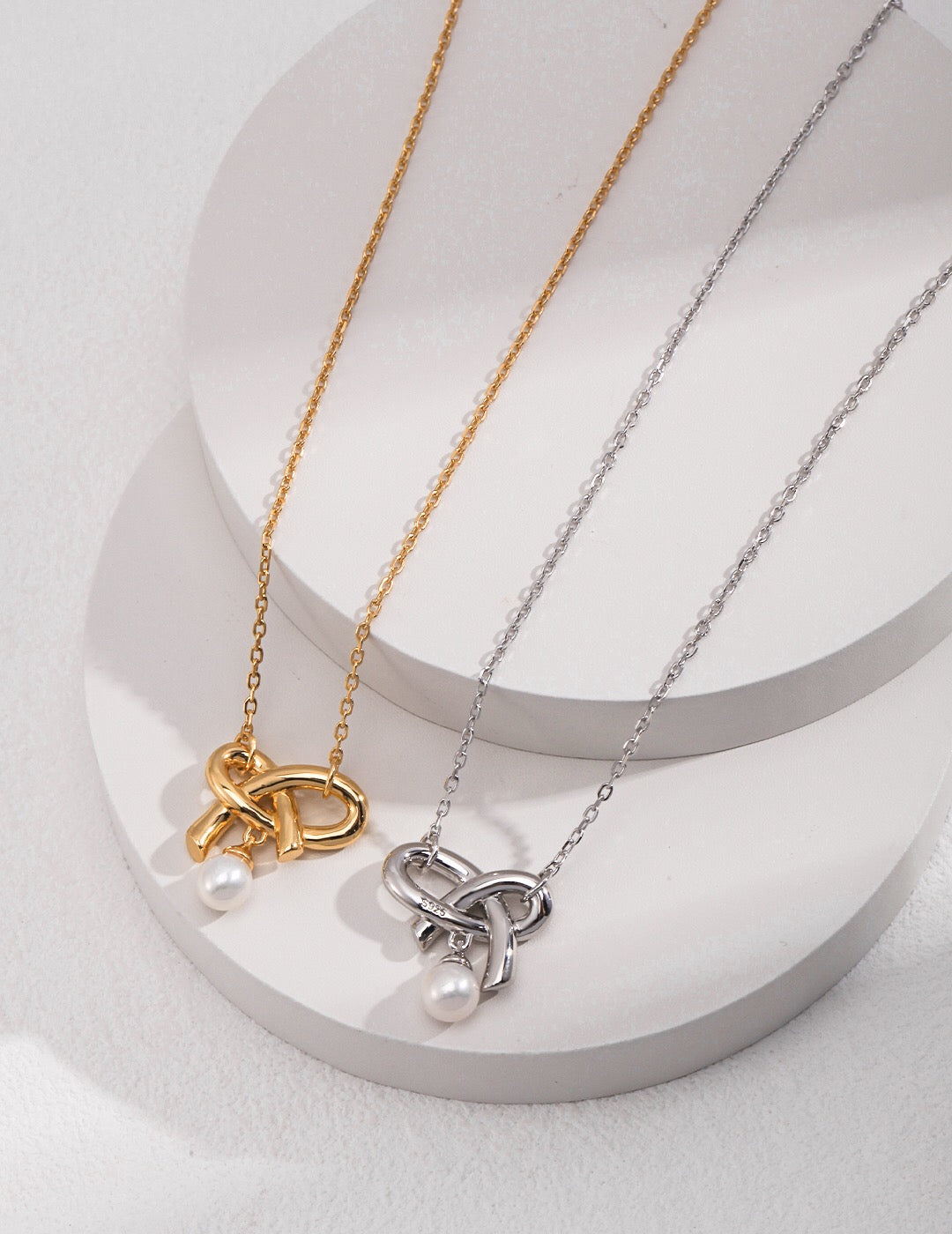 A delicate Love Bow Charm Necklace featuring a floating pearl, elegantly designed with gold vermeil accents.
