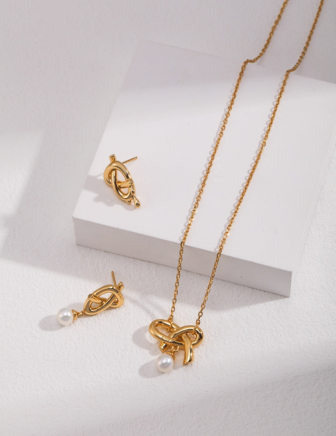 A delicate Love Bow Charm Necklace featuring a floating pearl, elegantly designed with gold vermeil accents.