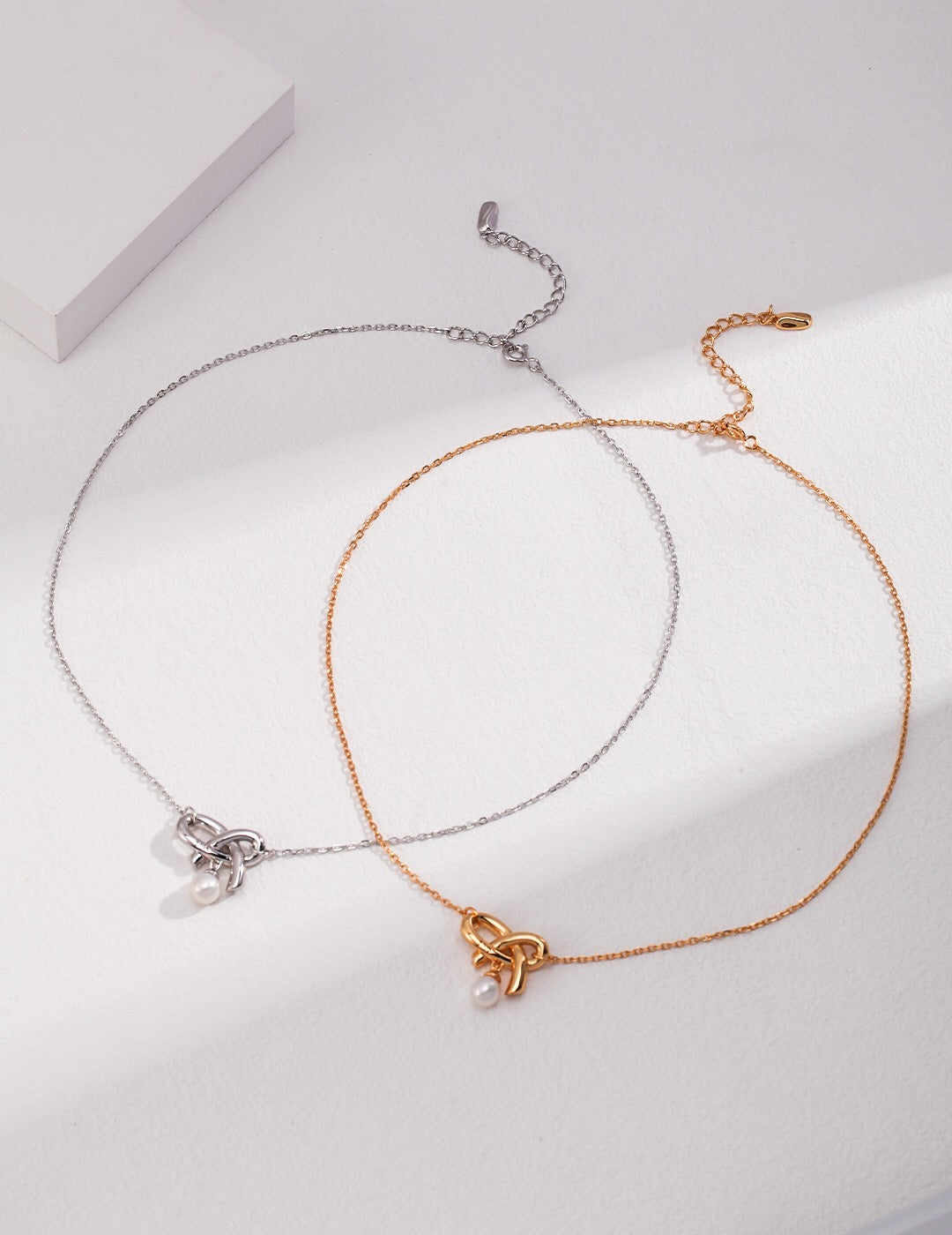 A delicate Love Bow Charm Necklace featuring a floating pearl, elegantly designed with gold vermeil accents.