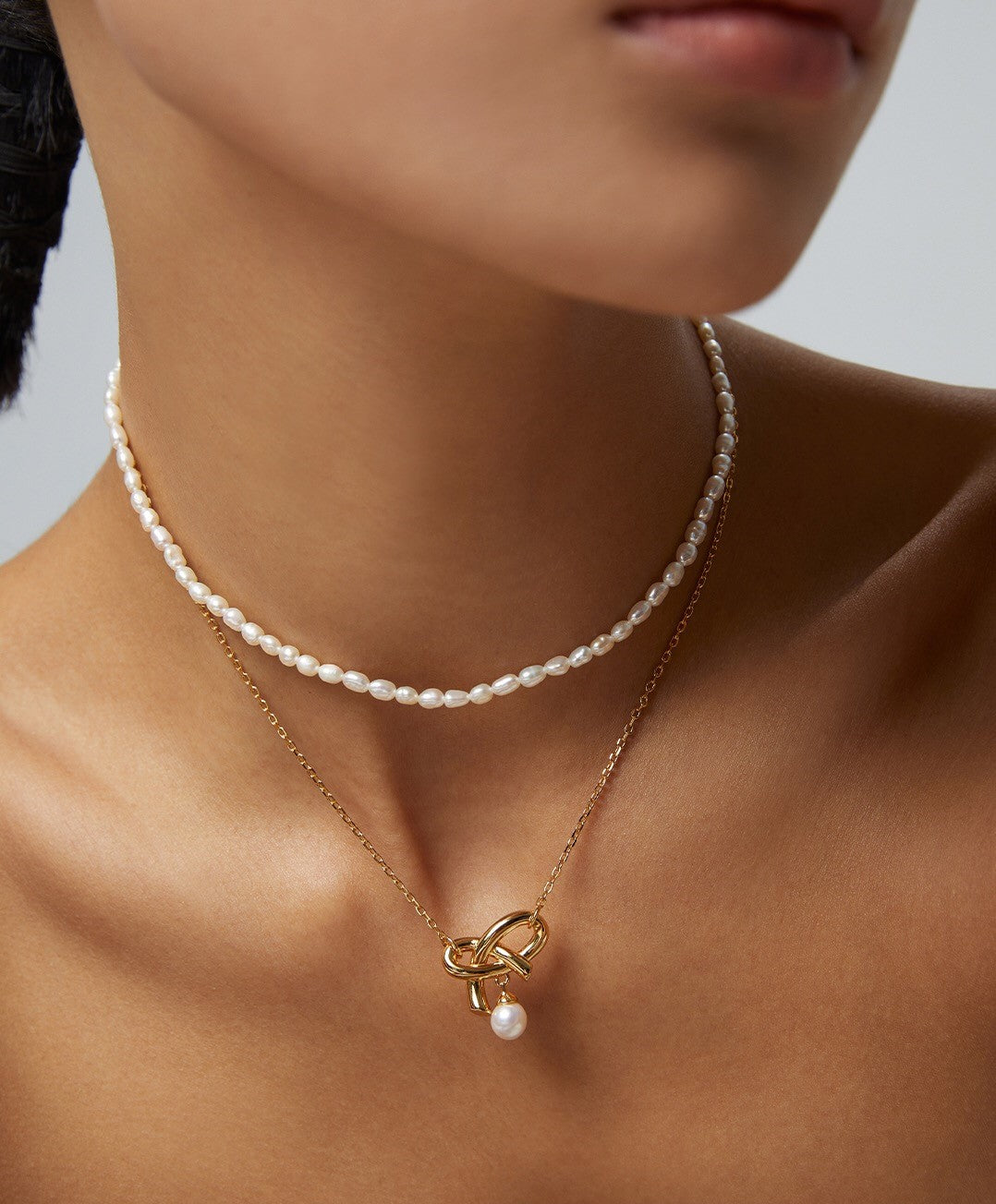 A delicate Love Bow Charm Necklace featuring a floating pearl, elegantly designed with gold vermeil accents.