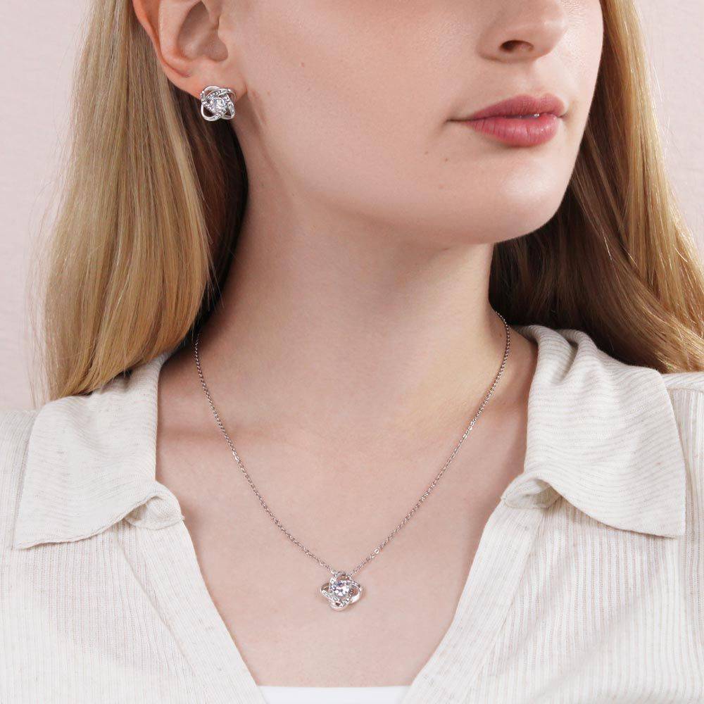Love Knot Earrings and Necklace Set featuring 14k white gold and cubic zirconia stones, elegantly displayed in a black velvet pouch.
