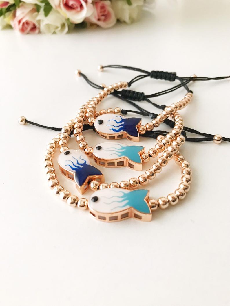 A beautiful rose gold beaded bracelet featuring a fish charm and an evil eye symbol, showcasing elegance and protection.